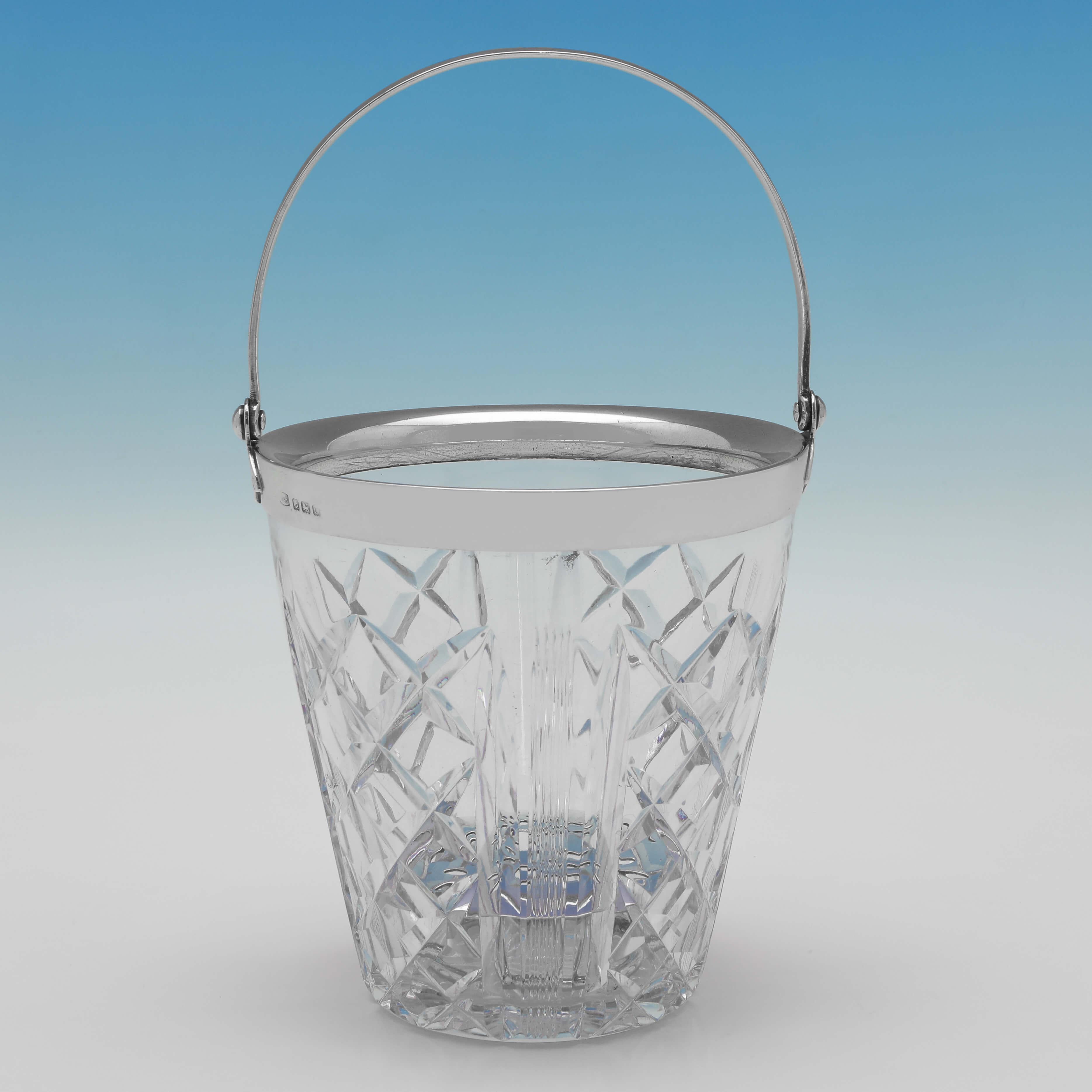Hallmarked in London in 1938 by Hukin & Heath, this handsome, glass & sterling silver ice bucket, is in the Art Deco taste. 

The ice bucket measures 5