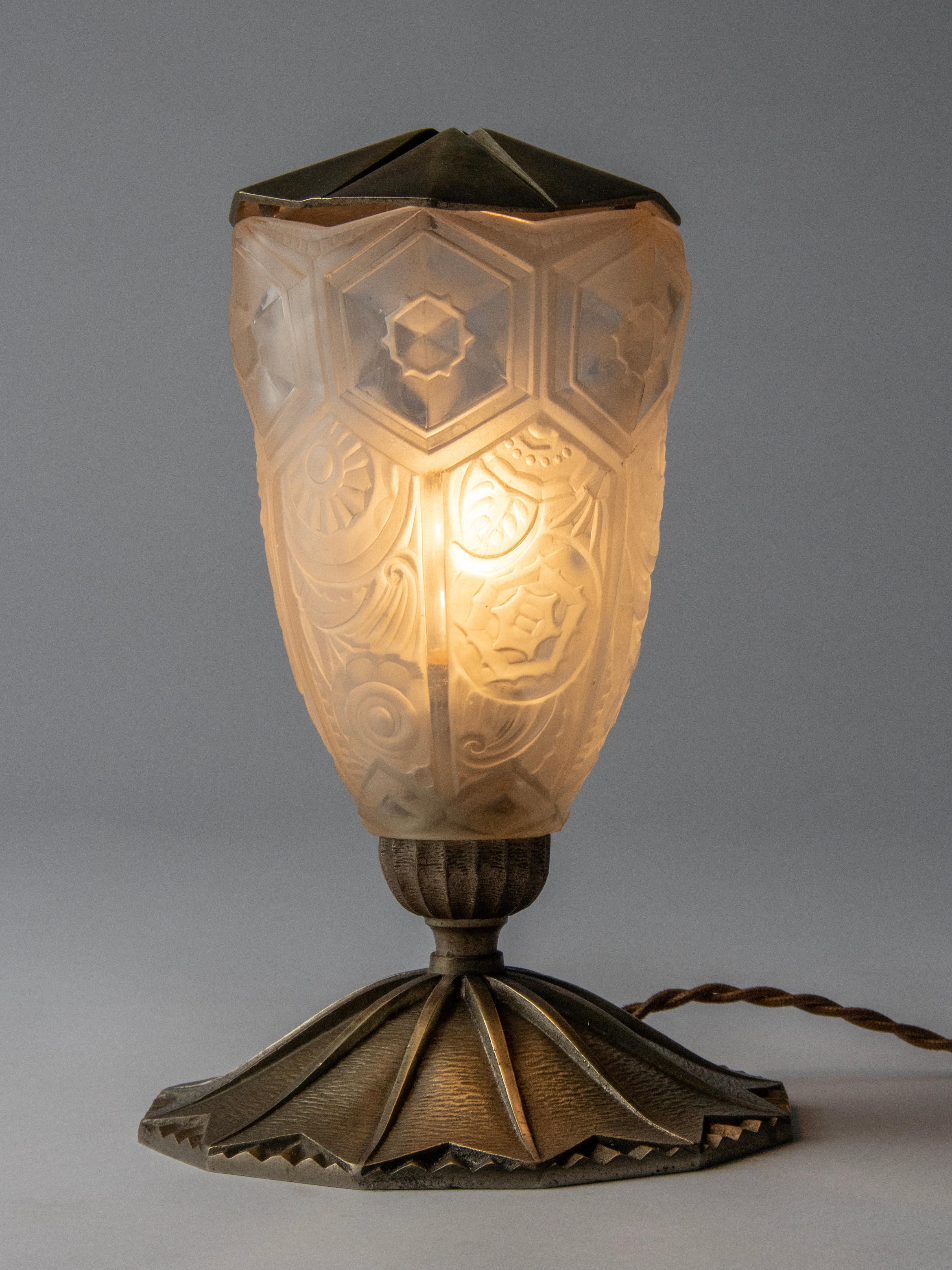 Une élégante lampe de table Art déco de la période Art déco française. Le pied et le couvercle sont en laiton nickelé. L'abat-jour est en verre moulé givré transparent avec des motifs floraux.
La lampe est en état de marche, elle possède le câblage