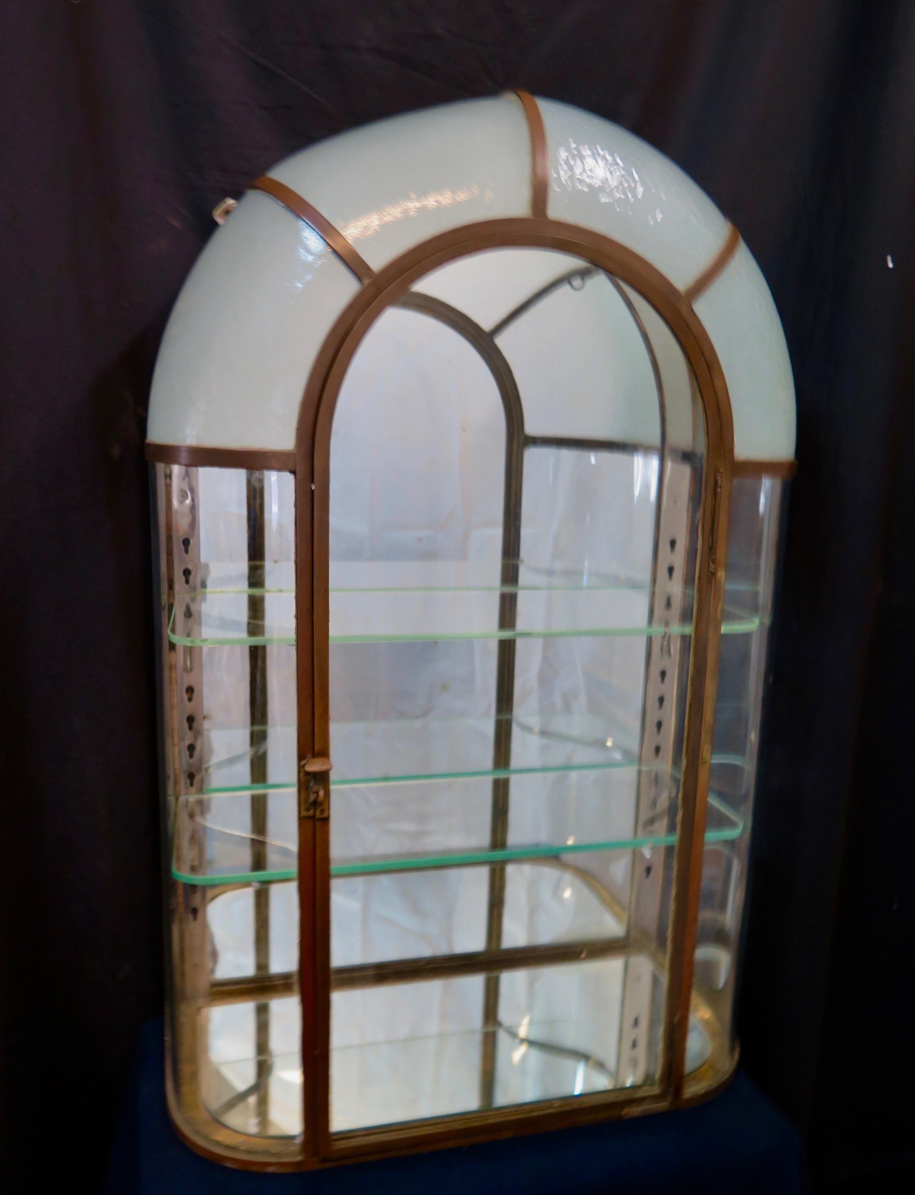 This wonderful Parisian perfume curio was designed by Joly & Co., 100 Rue de Roquette, Paris in the Art Deco period. This rare cabinet has a solid bronze frame, curved glass side panels, a bonnet of four curved textured & frosted glass panels & a