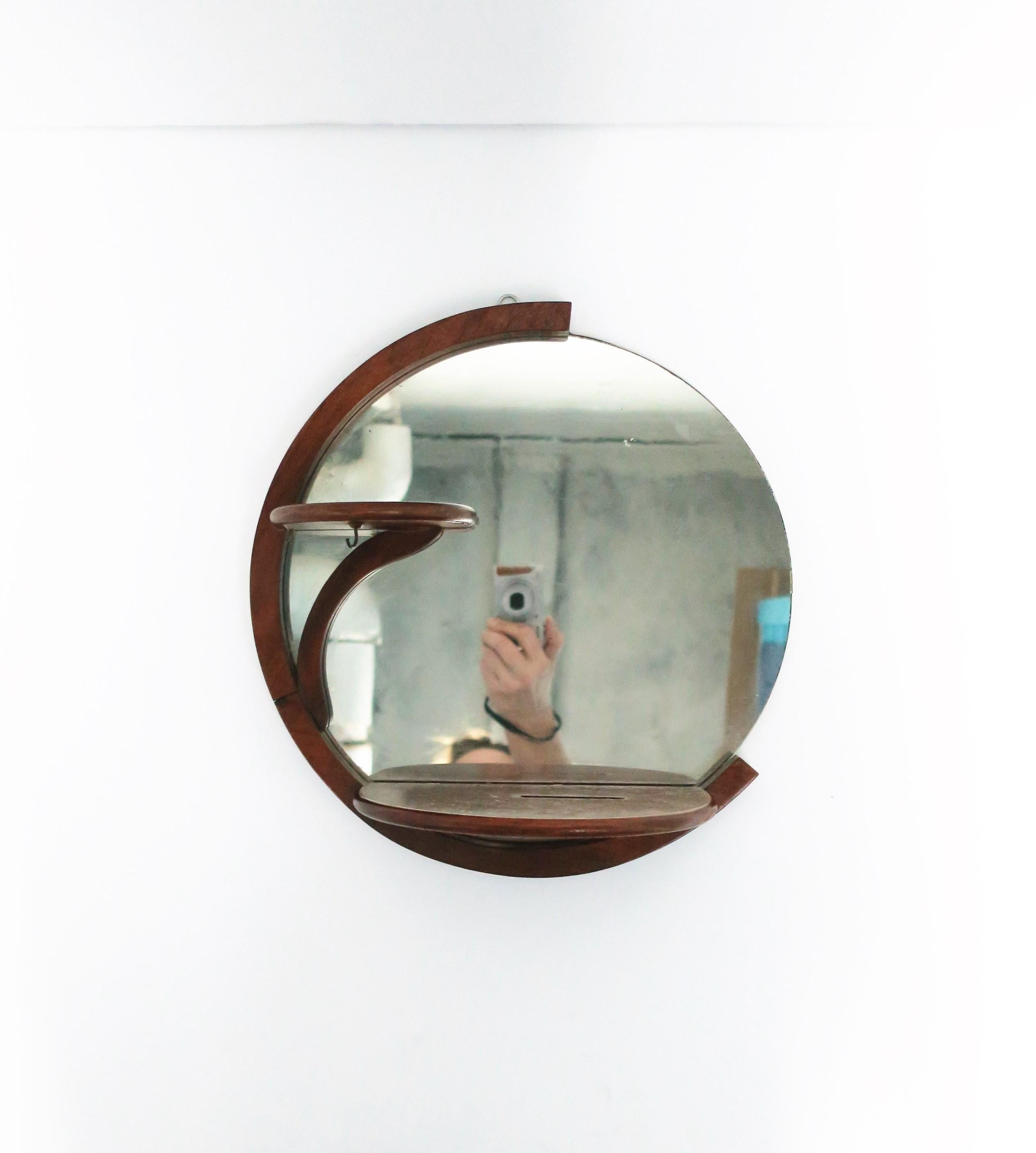 An Art Deco period round wood wall mirror with two shelves and small hook, circa 1940s. A great mirror for a vanity, walk-in-closet area, etc. Dimensions: 5