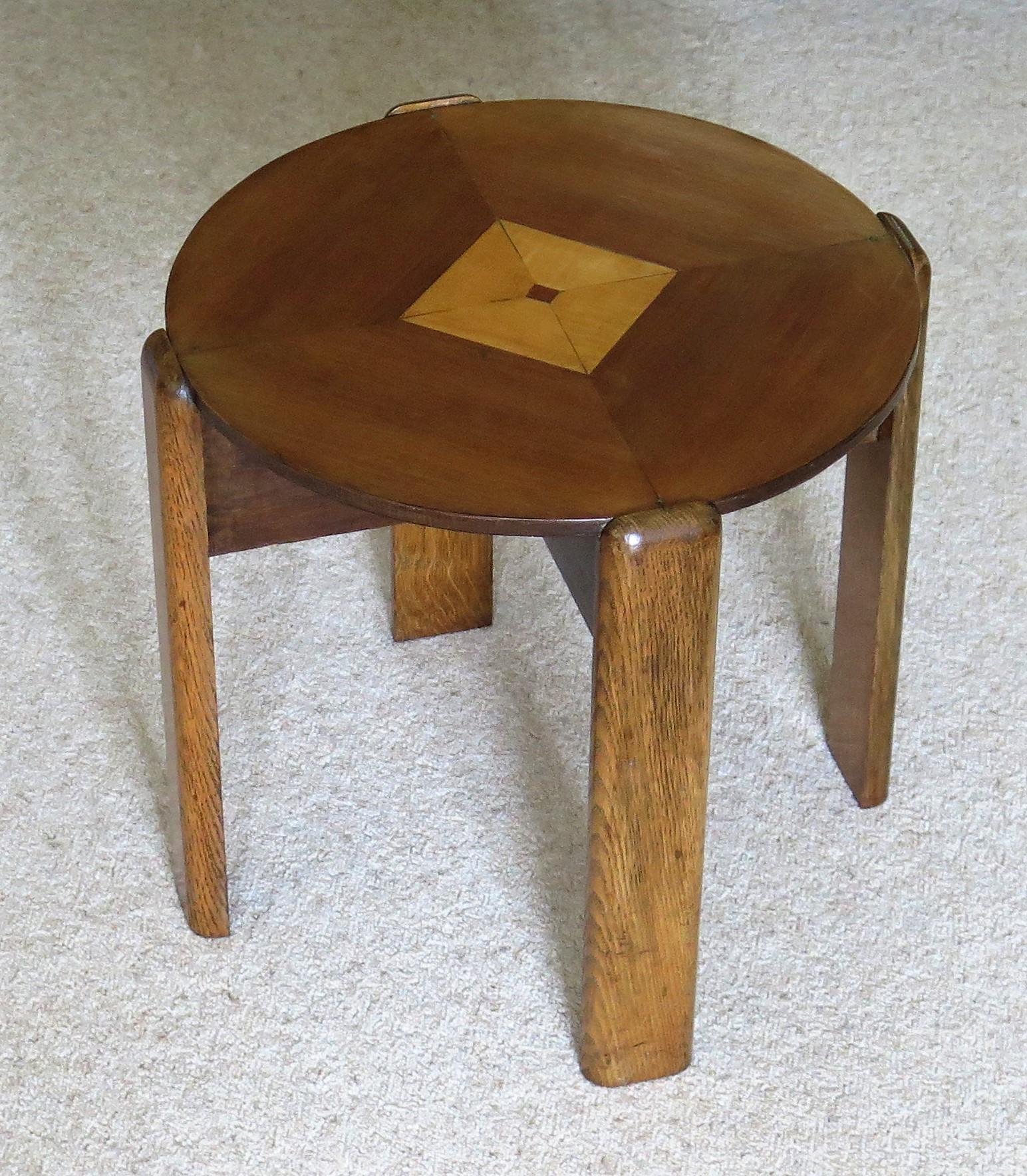 This is a very decorative occasional, end or side table made from different hardwoods in a typical geometric design and dating to the Art Deco period, circa 1930.

The table has a circular top sitting on an X-frame support with four shaped oak legs