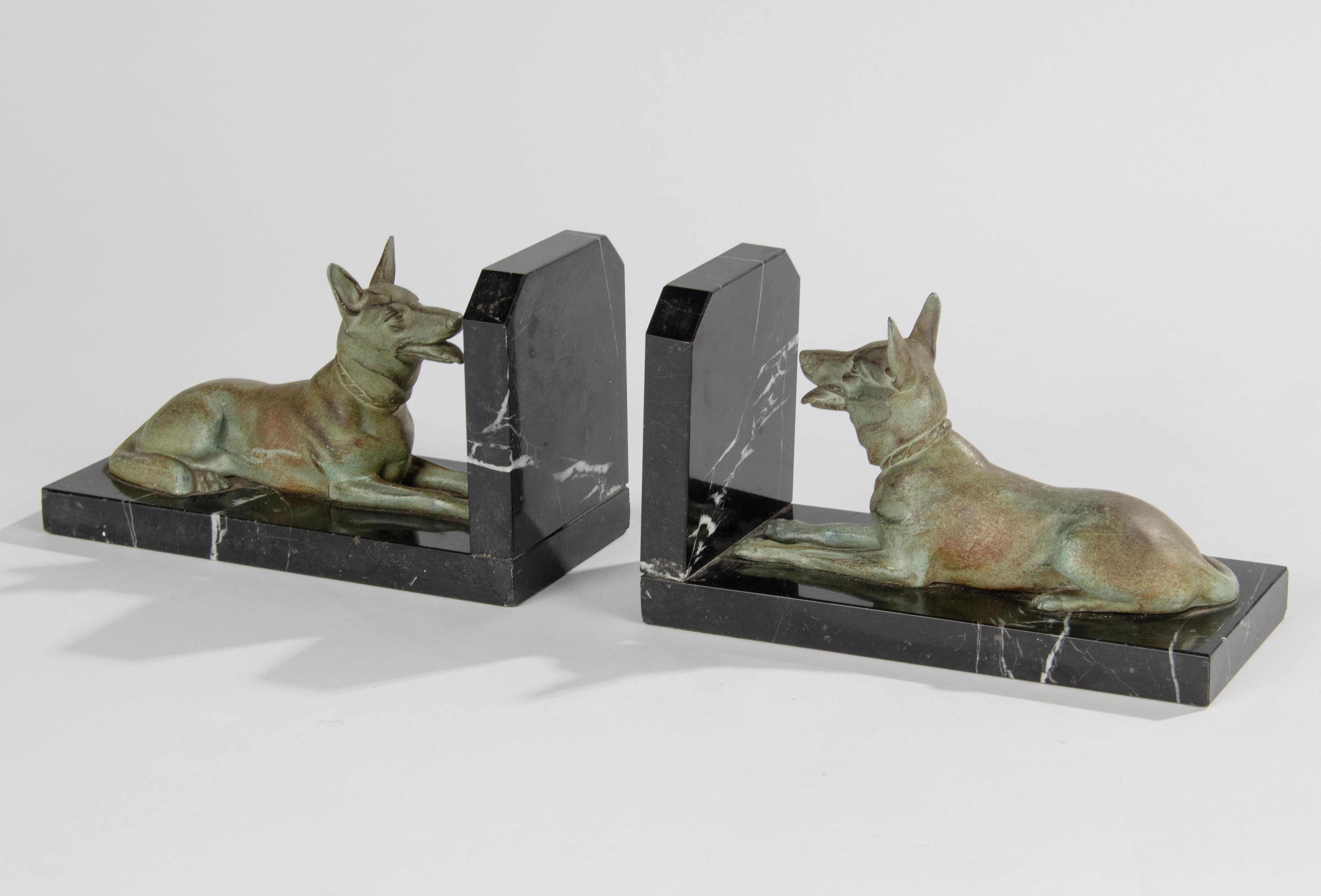 A pair of Art Deco period bookends, with sculptures of German or Belgian shepherd dogs. The figurines are made of green patinated spelter (zinc alloy). The plinths are made of Black marble with white veins. Marble and figurines are in good