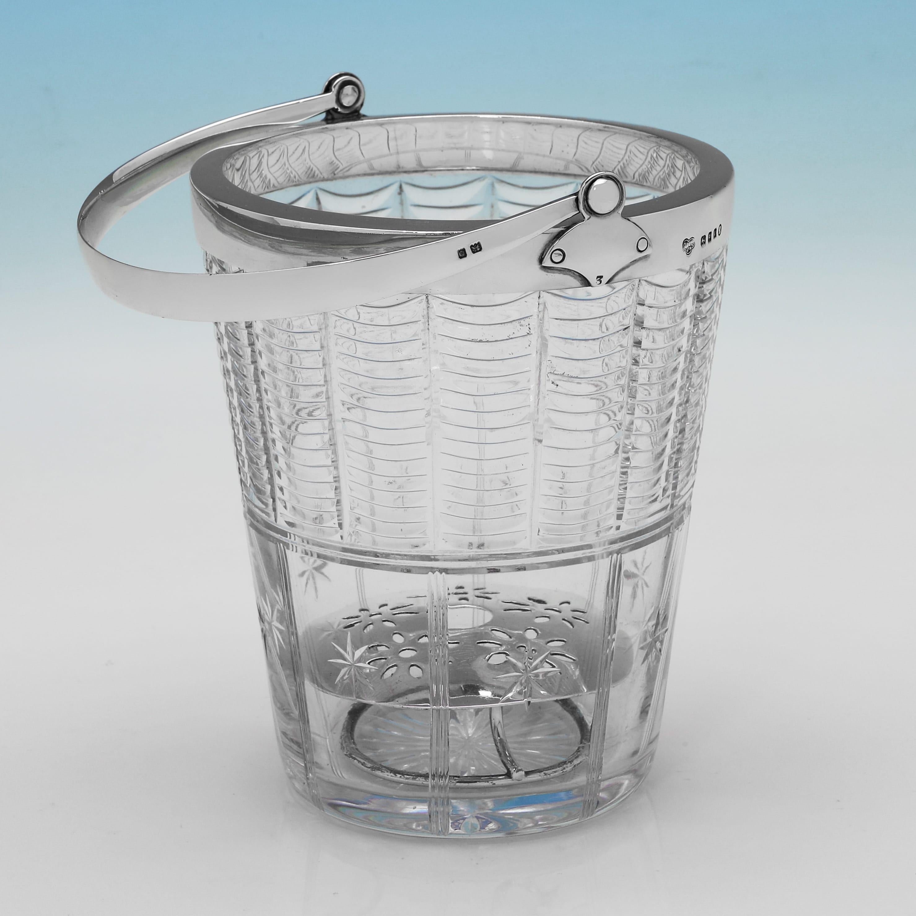 Poinçonné à Londres en 1934 par Goldsmiths & Silversmiths Co, cet élégant seau à glace en argent sterling et verre d'époque George V est dans le goût art déco, avec un corps en verre nervuré, une monture et une poignée en argent uni, et une passoire