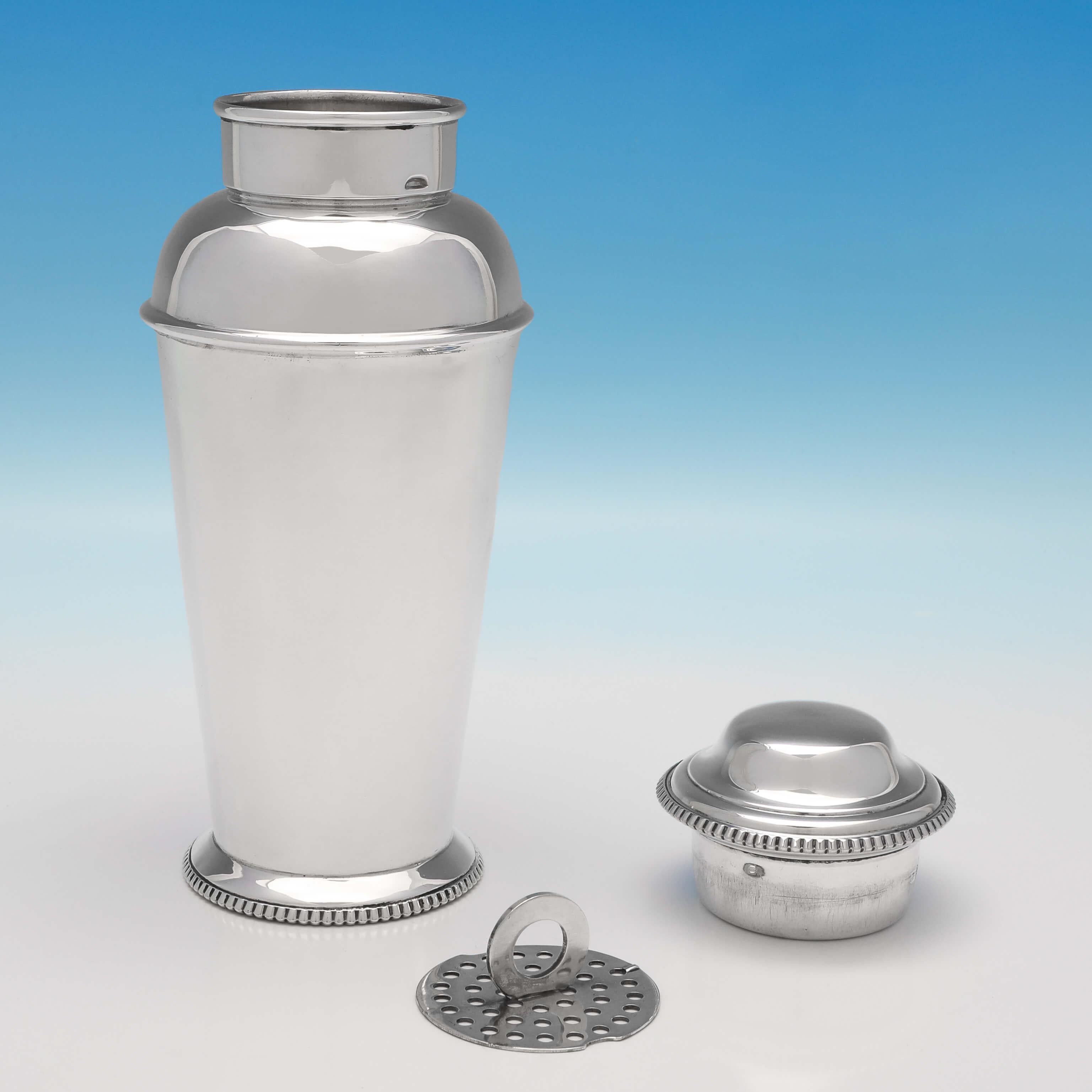 Hallmarked in Birmingham in 1929 by Adie Brothers, this handsome, Art Deco, sterling silver cocktail shaker, is simple in style, with egg and dart borders around the lid and base, and features a removable strainer. The cocktail shaker measures 9
