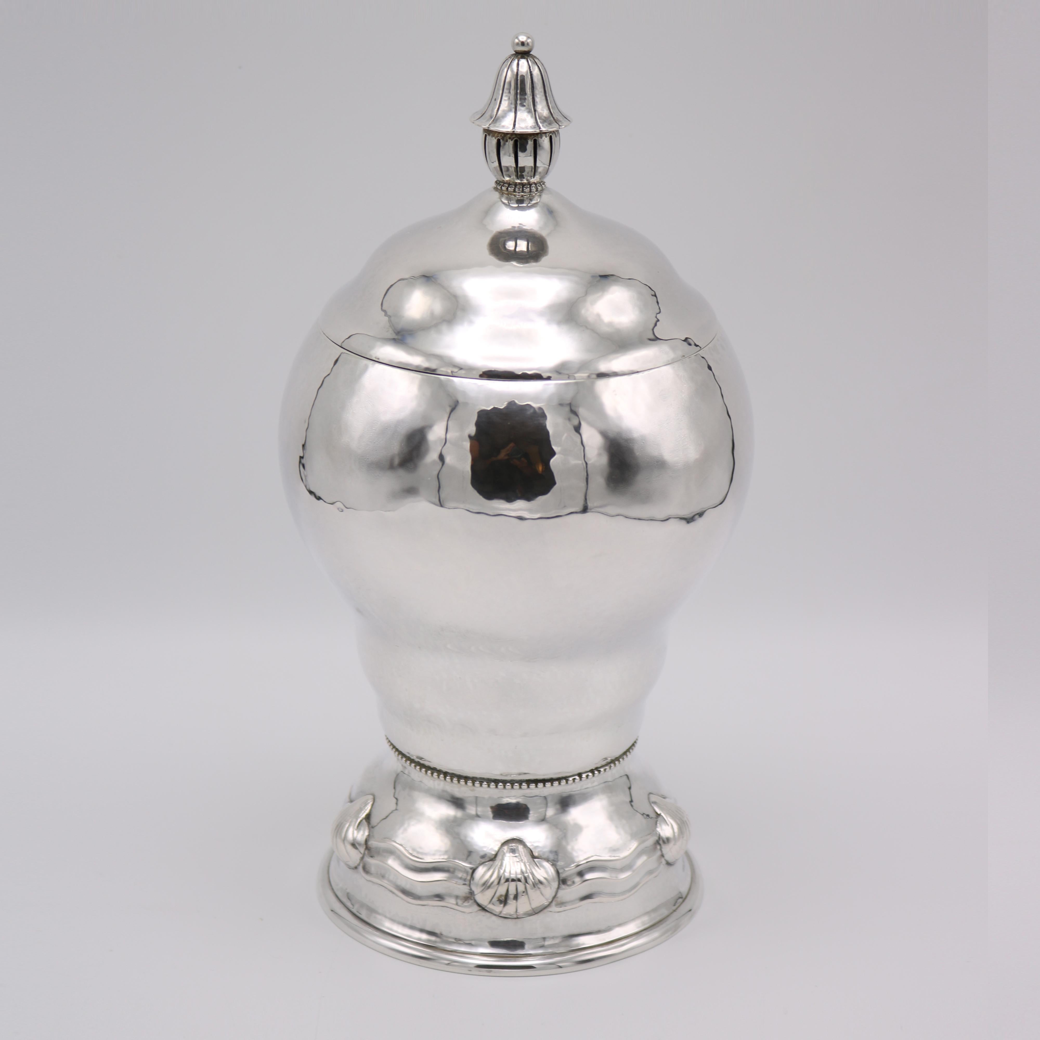 Vaso rivestito in argento sterling di epoca Art Deco, proveniente dalla Germania, circa 1930. 
La forma rotonda a balaustro è sormontata da un coperchio che si rimuove afferrando l'importante terminale. 