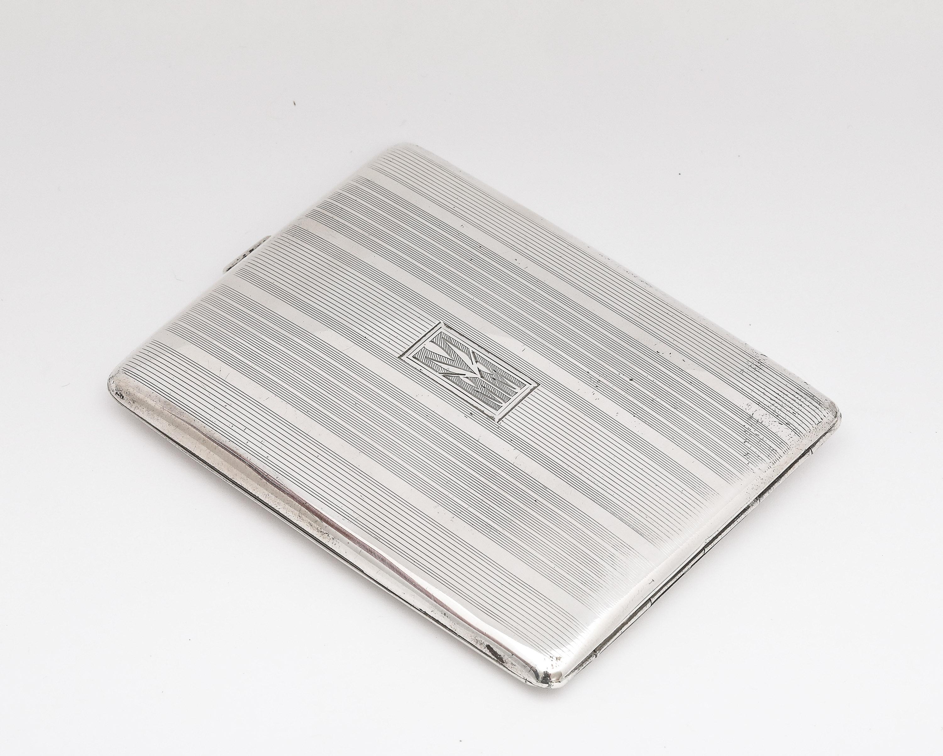 Portasigarette/cartolina in argento Sterling, periodo Art Deco, America, ca. 1930, con un disegno a strisce di smoking sul coperchio. Interni dorati. Il coperchio con cerniera presenta un cartiglio con inciso MMM in un carattere Art Deco (vedi foto)