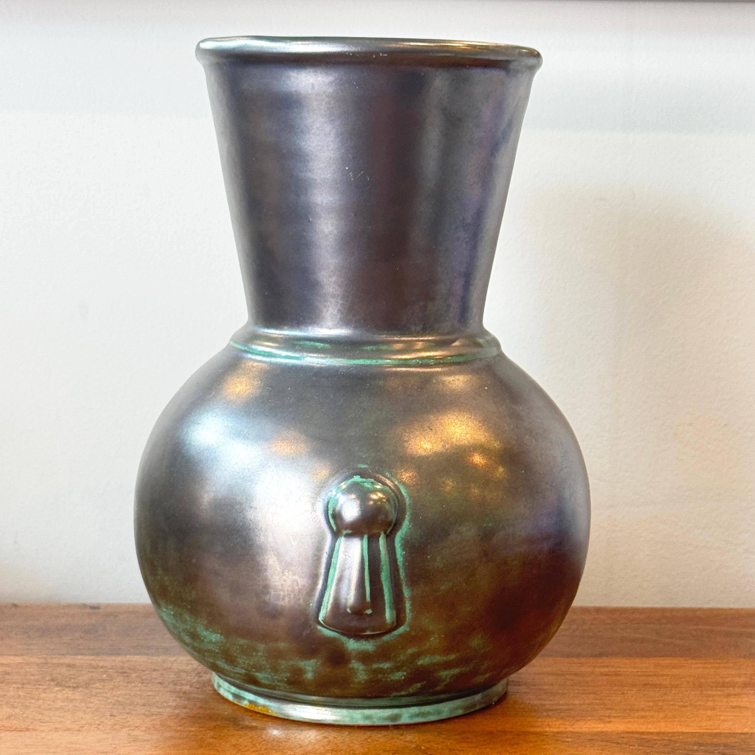 Ce magnifique vase d'époque Art déco, Swedish Grace, a été conçu par Einar Luterkort pour Upsala Ekeby vers 1930. Décoré d'une glaçure argentée sur fond vert, le vase a un col évasé en forme de trompette et est moulé avec des poignées en forme de