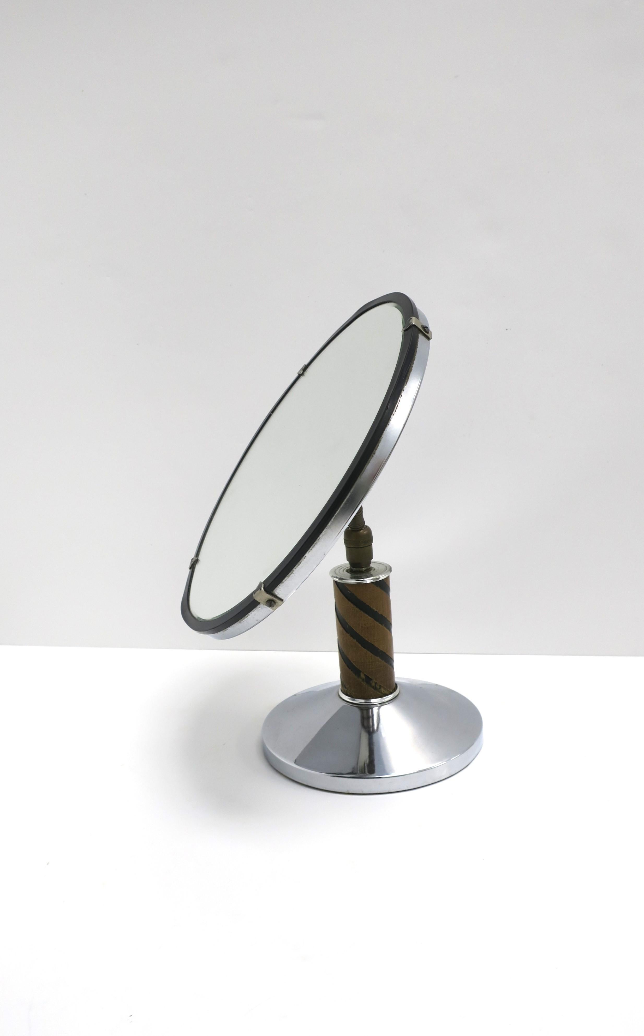 A chrome and wood Art Deco period table vanity mirror, circa early-20th century. Piece has wood and chrome metal base and frame, round mirror, and bronze hardware at back. Mirror is adjustable as shown (up, down, left, right.)

Dimensions: