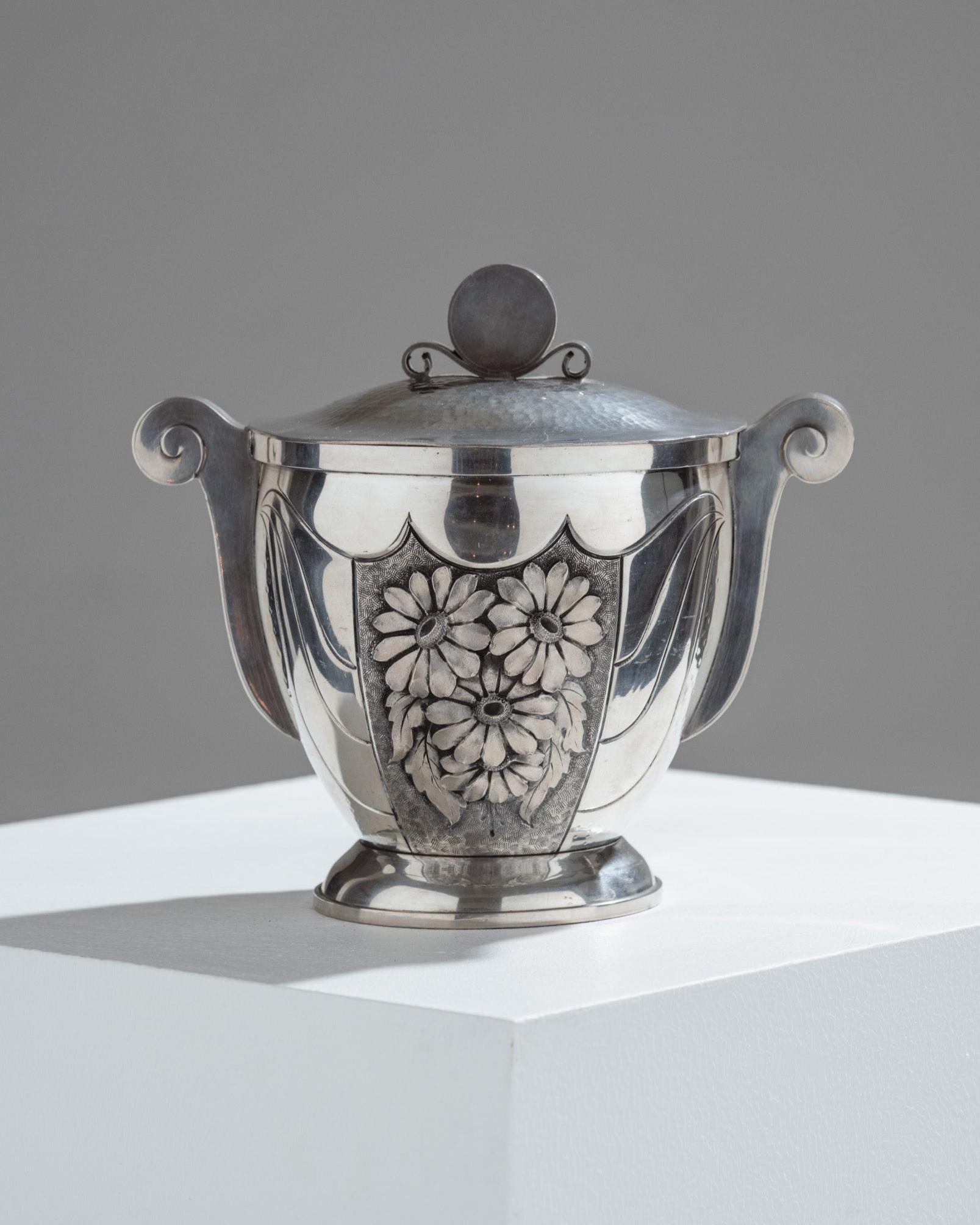 Repoussé pewter candy box signed R.S. Paris (René Sitoleux), circa 1940.
Covered jar with a floral motif on the front and a scroll-shaped handle. Signed on the underside. Excellent condition.

DV4385