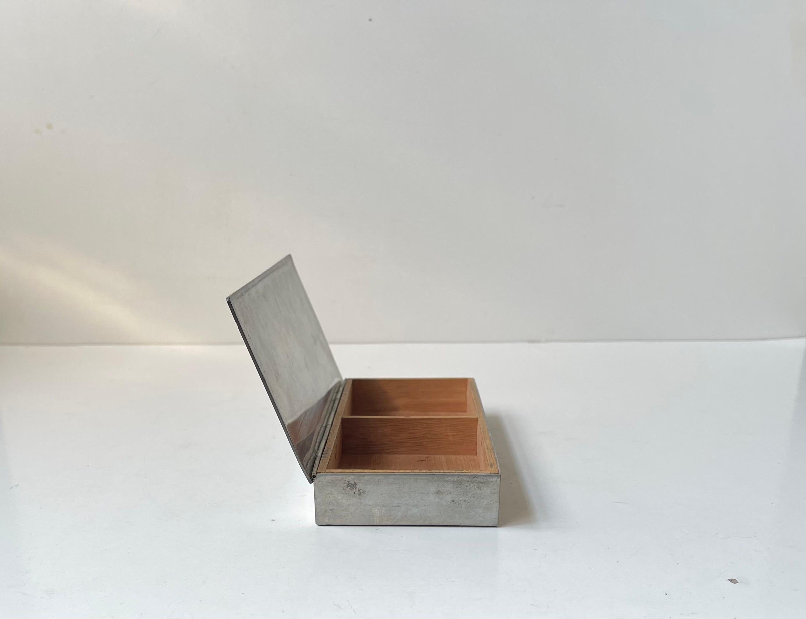 Simplicity and clean design comes to mind observing the pewter box designed by Just Andersen in Denmark during the mid-late 1930s. It's linen with cedar wood and suitable for storing cigarettes or playing cards. Its stamped Just, Denmark, 2494 to