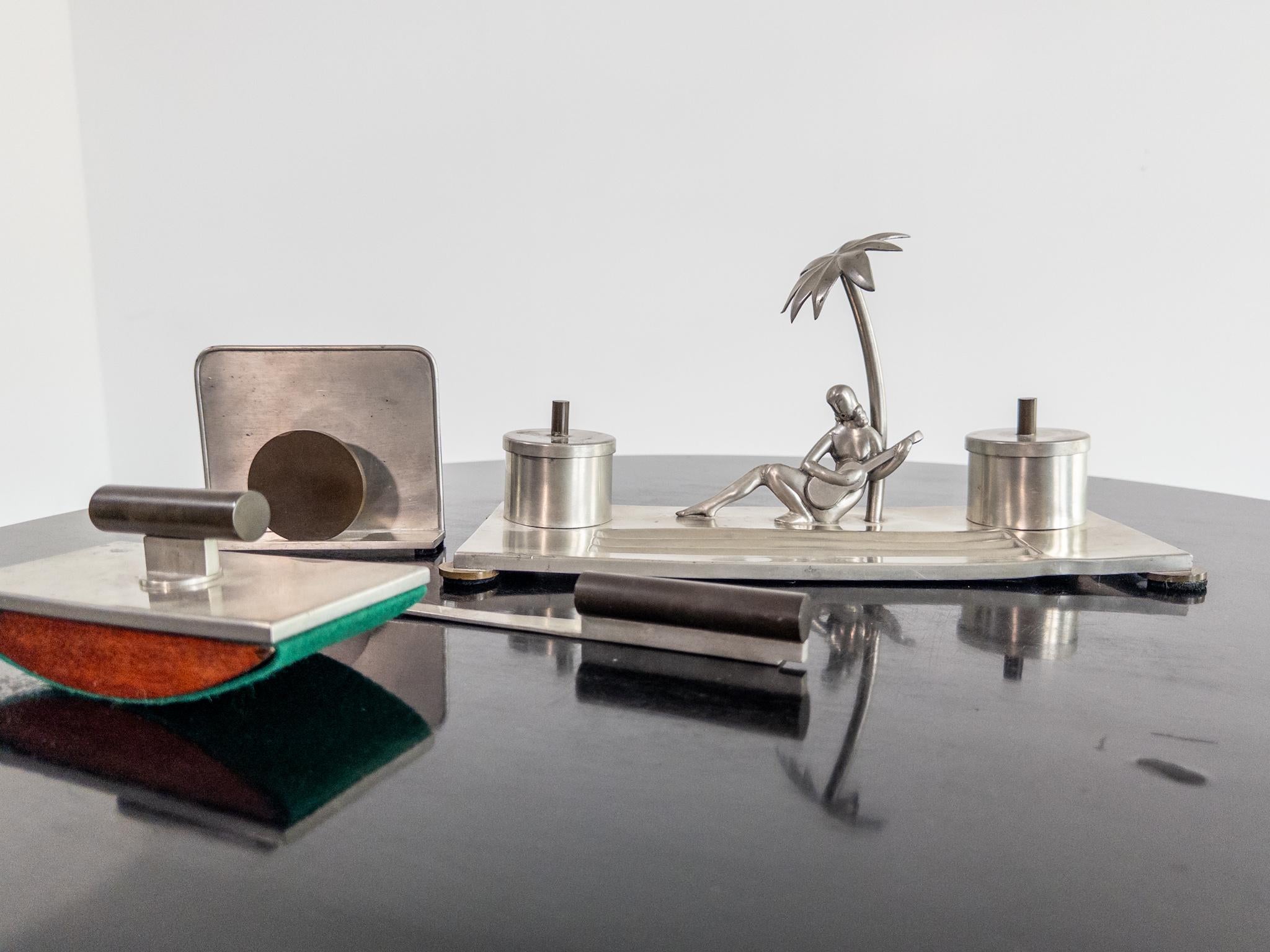 Un elegante e raro set da scrivania di 4 pezzi disegnato da Carl-Einar Borgström per Ystad Tenn, Svezia. Realizzato in peltro con dettagli in bachelite, questo set Art Deco comprende:

- Calamaio con scena tropicale scultorea
- Tagliacarte
- Porta
