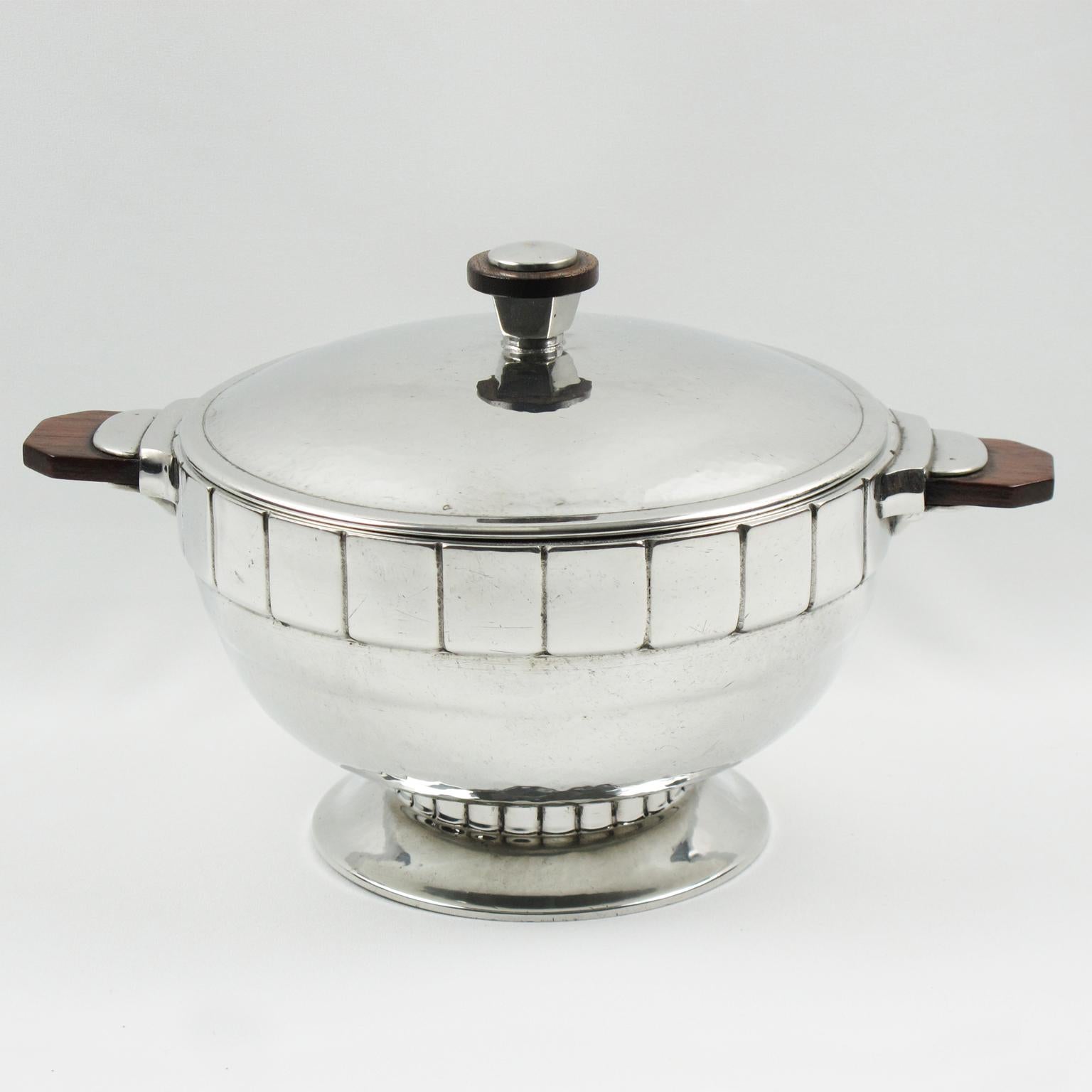 H. J. Swiss Pewter ha progettato questo splendido centrotavola o piatto coperto in peltro lucido in rilievo Art Deco. Il pezzo è stato realizzato in Svizzera nel 1940 circa. La zuppiera ha un'elegante forma modernista in peltro lucido con un design
