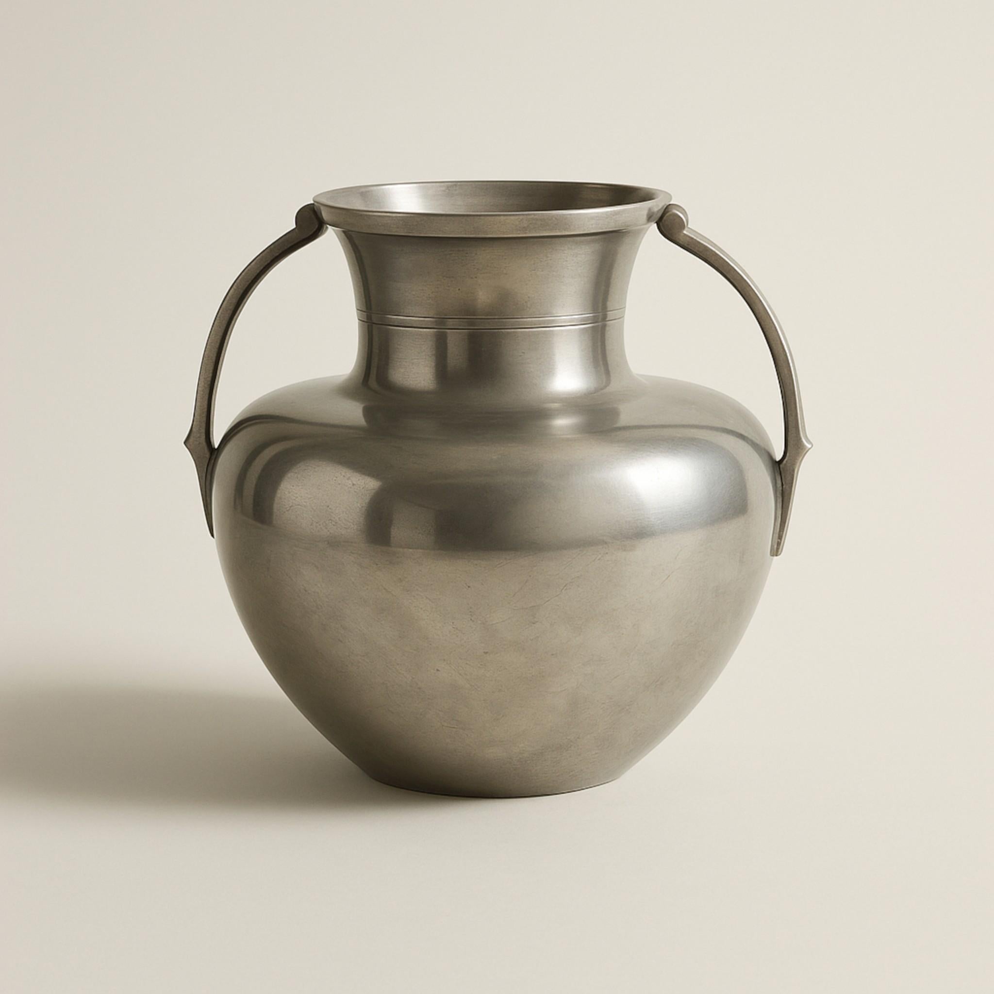 Elegant vase en étain fabriqué par GAB (Guldsmedsaktiebolaget) en Suède, daté de 1935. Cette pièce magnifiquement équilibrée présente une forme classique inspirée des amphores avec deux poignées sculptées et une douce finition satinée qui met en