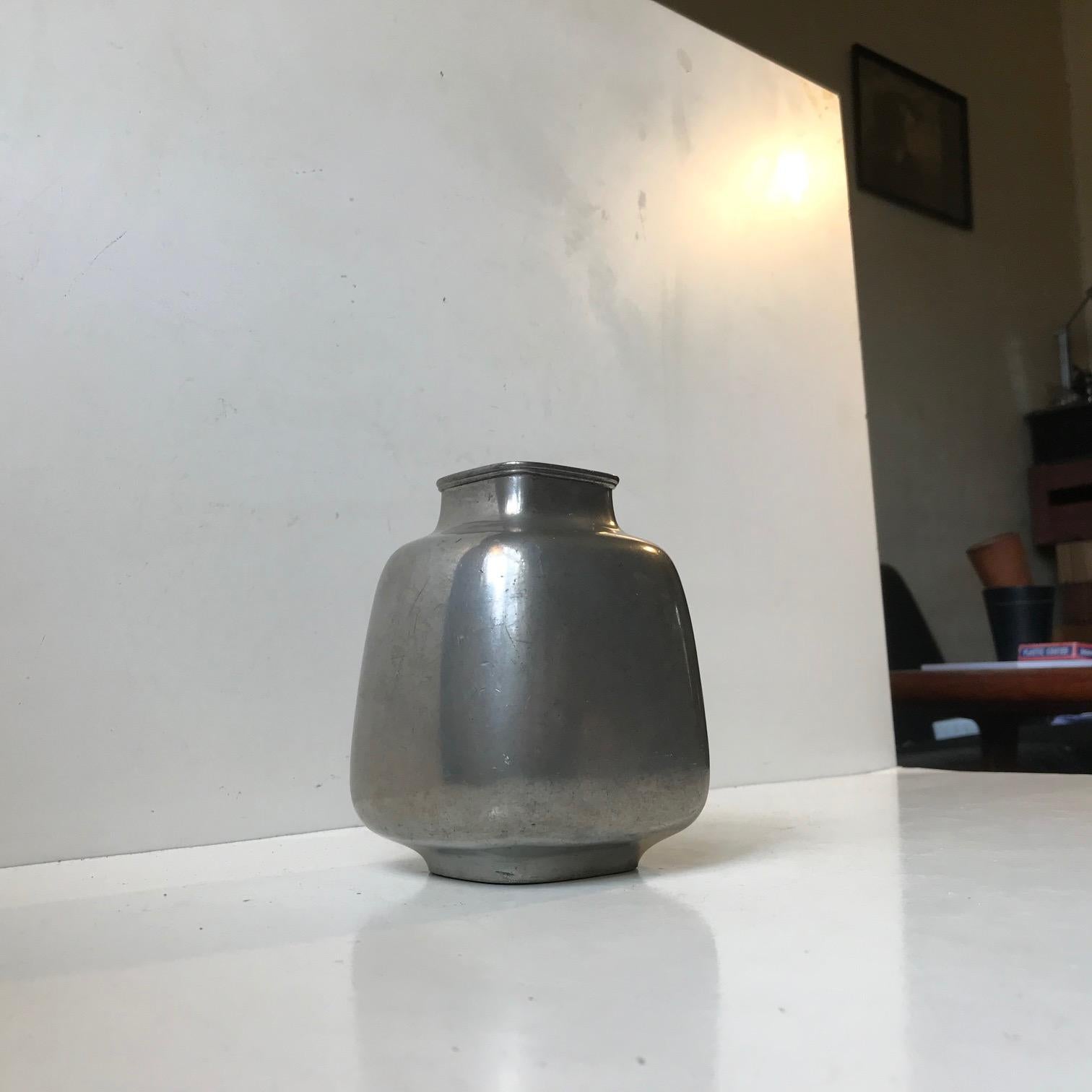 A Pewter vase that in shape fusions square and circular. Designed and manufactured by Just Andersen in Denmark during the 1930s. Imprinted to its base: Just, Danmark, 2707. Measurements: H 13.5 cm, W/D 10/5.5 cm.