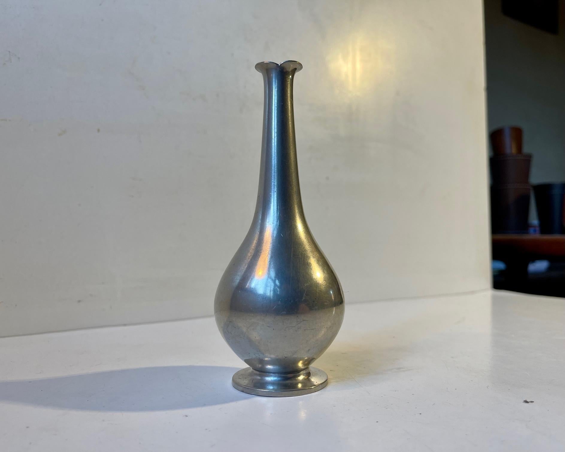 Un petit vase en étain avec un long col. Conçu et fabriqué par Just Andersen au Danemark dans les années 1930. Imprimé à sa base : Just, Danmark, 1157. Dimensions : H : 14,5 cm, L/D : 5,5 cm.