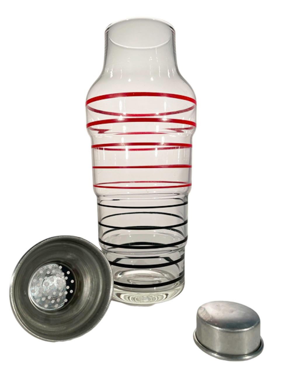 Large Art Deco cobbler type cocktail shaker of clear glass of stepped tapering form with aluminum lid and cap. The clear glass painted with red lines above black lines and with the line widths narrowing toward the center. This shaker is in the style