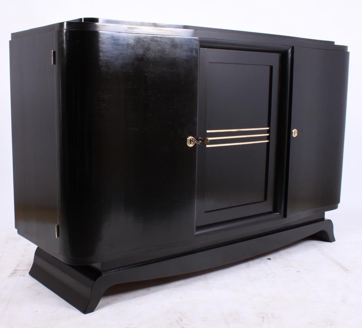 Art Deco piano lacquer black sideboard
A French Art Deco sideboard with three doors in a ebonized piano lacquer finish having brass detail doors and locks all working with 2 keys supplied very good condition throughout

The sideboard can