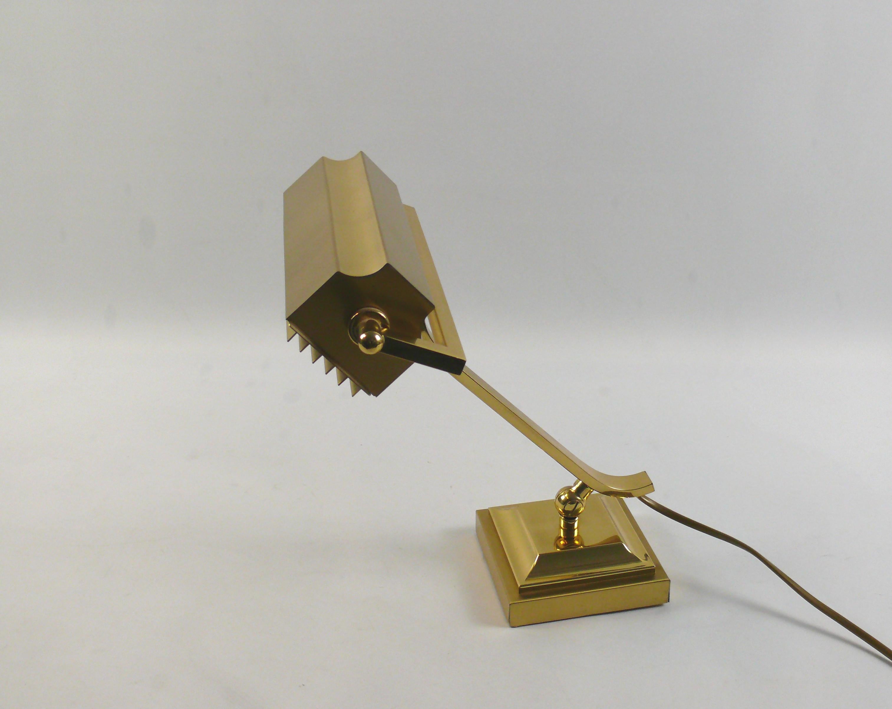 Rare, very solid and heavy piano lamp made of brass, circa 1960s - 1970s with removable glare protection. The lamp is made of shiny brass with almost no signs of aging on the brass surface. The umbrella and the arm can be adjusted. The joint can be