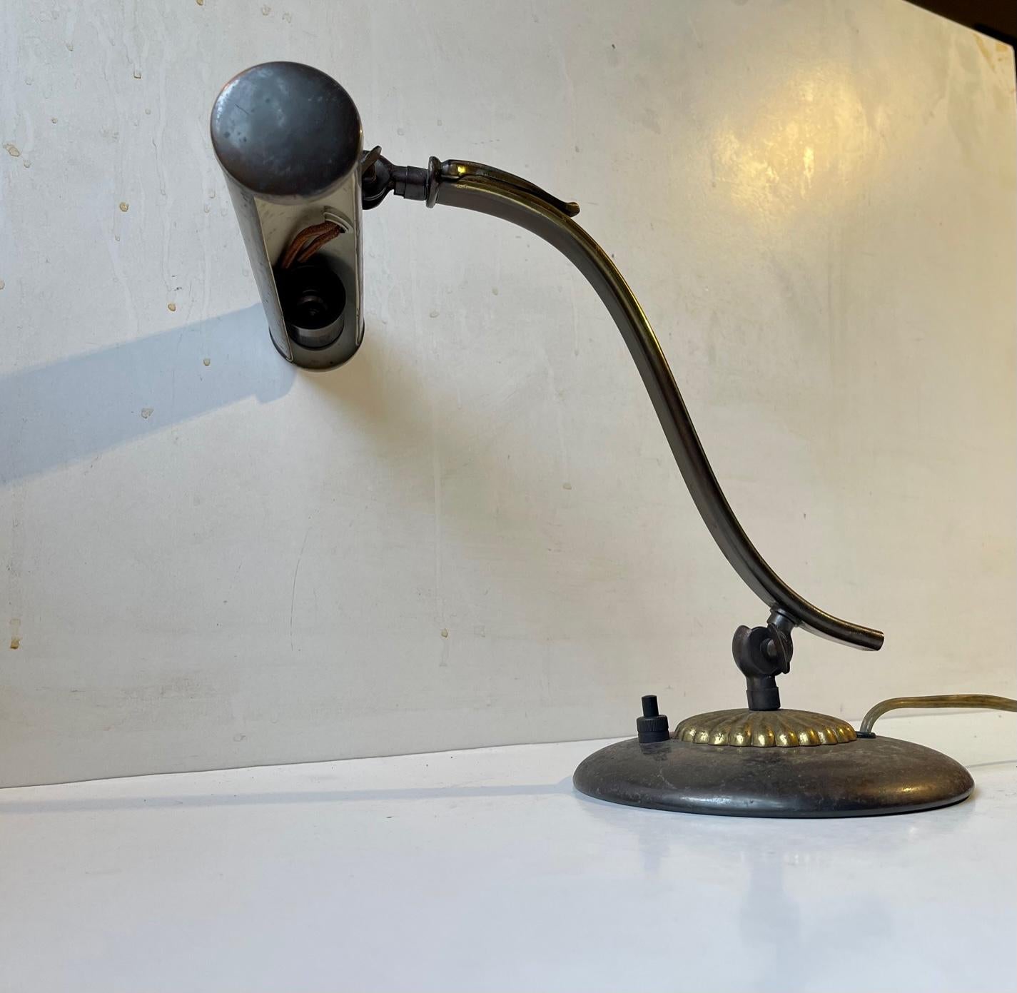 Adjustable piano lamp with classic tubular shade. It made from brass and is partially patinated. Made in Scandinavia, presumably Denmark circa 1930-40. Working order. Measurements: H: 28 cm, Shade: 20x4,5 cm. The base has a diameter of 15 cm. For