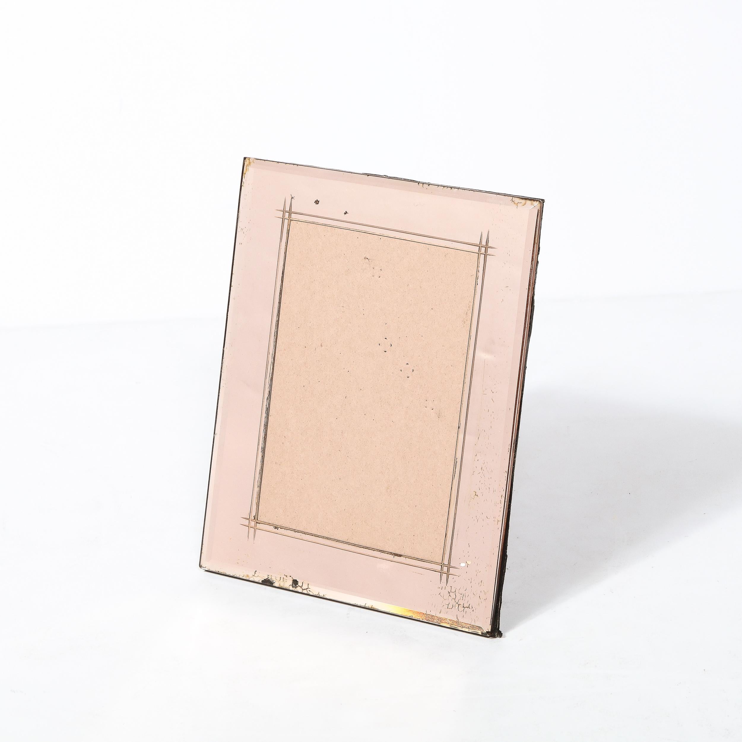 This picture frame is crafted in the United States, circa 1935, beautifully rendered Smoked Rose Glass. The frame is rectangular with Beveled Edge Detailing and utilizes reverse etching which draws the eyes towards the center of the piece and