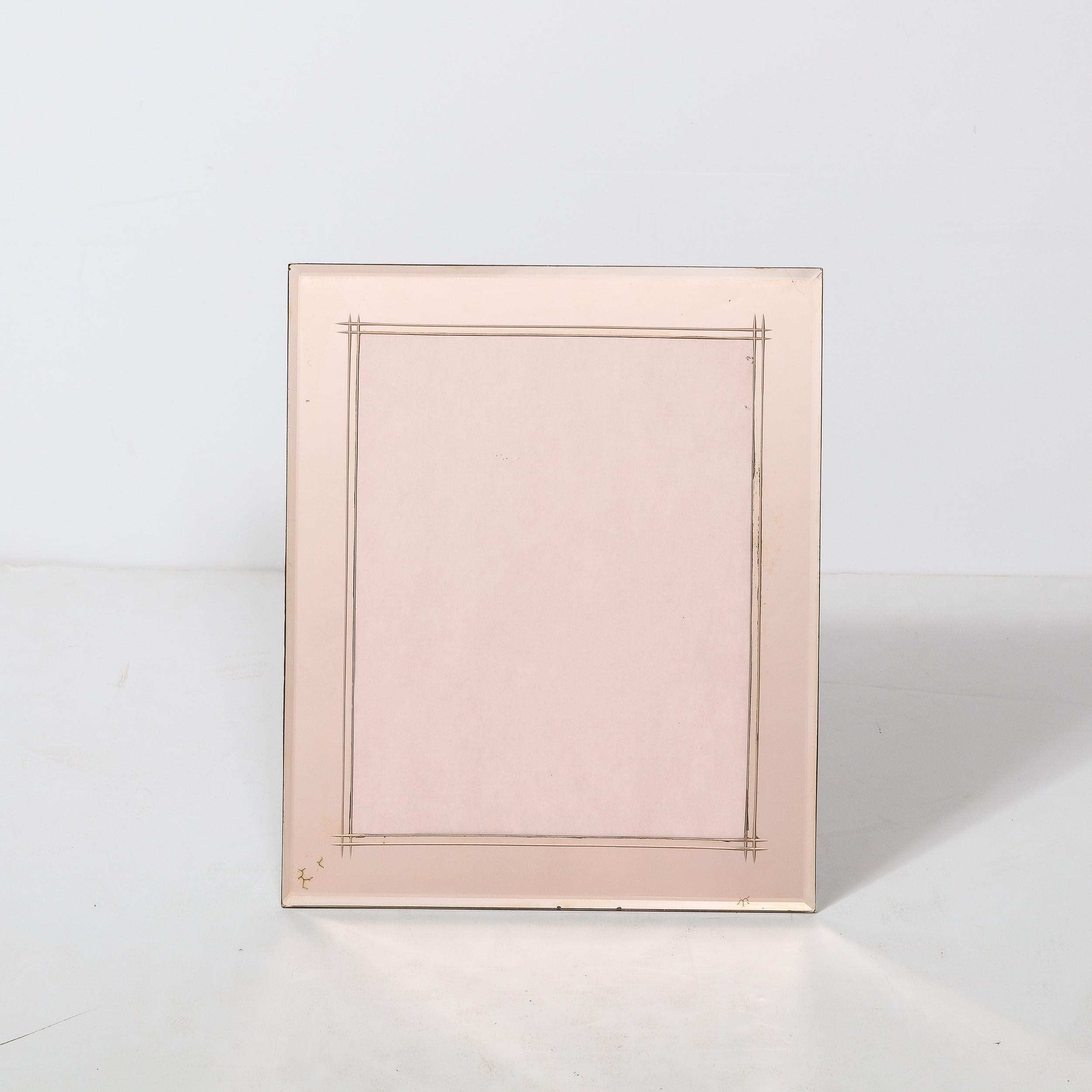 This picture frame is crafted in the United States, circa 1935, beautifully rendered Smoked Rose Glass. The frame is rectangular with Beveled Edge Detailing and utilizes reverse etching which draws the eyes towards the center of the piece and