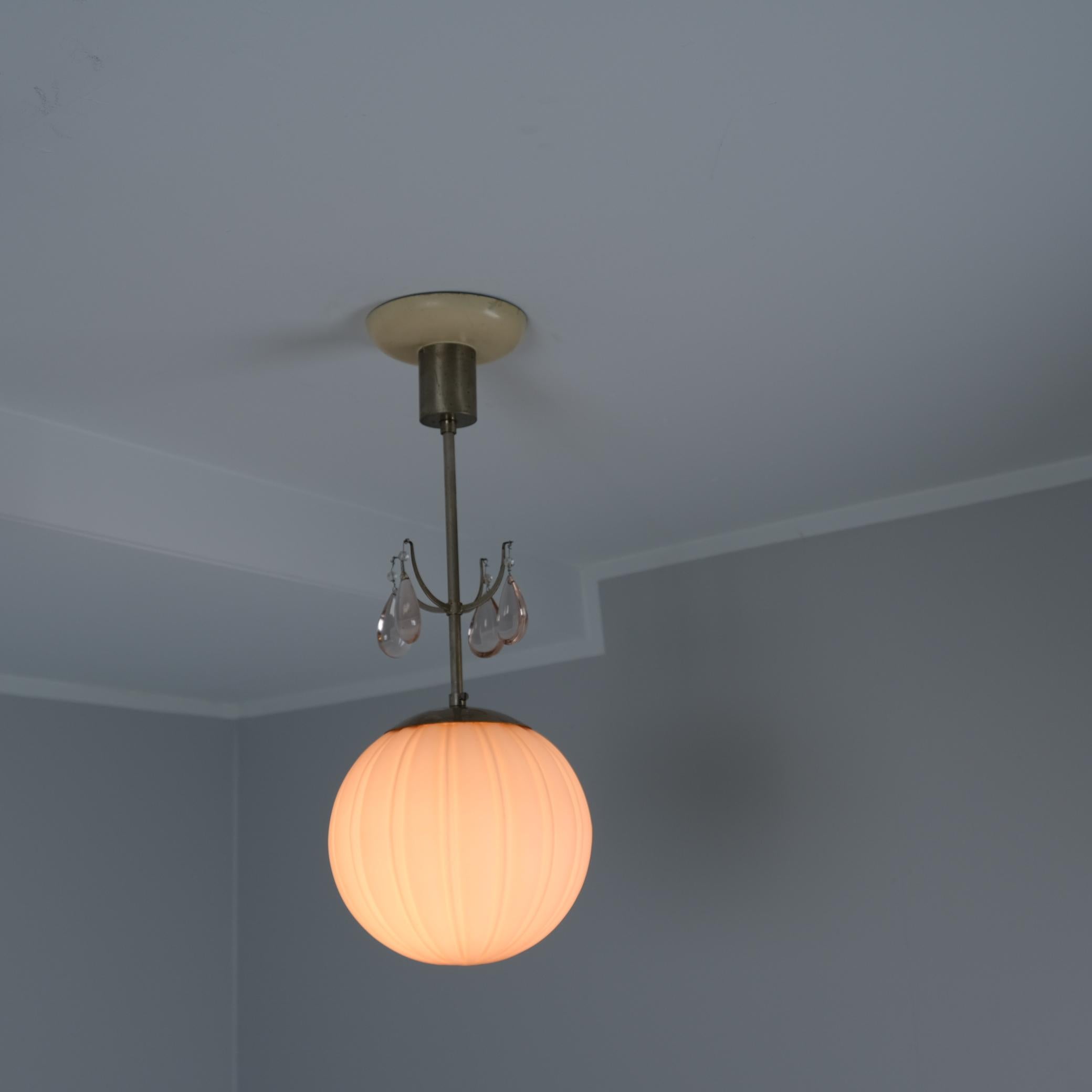 Un bellissimo paralume a sfera in ottone nichelato art déco e vetro rosa con decorazioni in cristallo rosa sullo stelo. La lampada è un bellissimo pezzo art déco che rappresenta la grazia svedese degli anni Venti-Trenta. La lampada è prodotta da