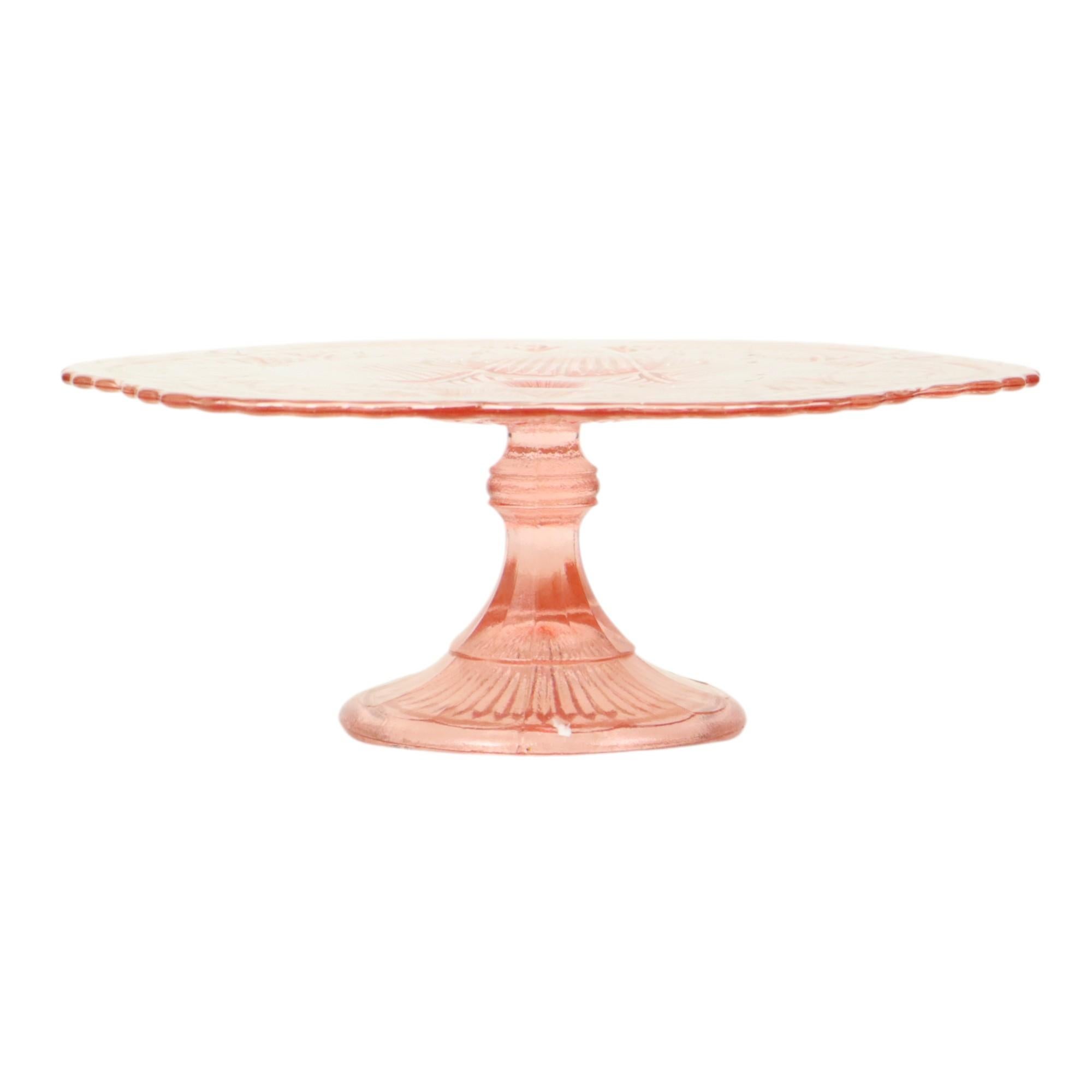 A beautiful, large, vintage pink cake stand with a floral, diamond, and star pattern. It features an elegant, wavy edge along the outside. It is made of pressed colored glass, also known as Depression glass, from the Art Deco period. It is unmarked