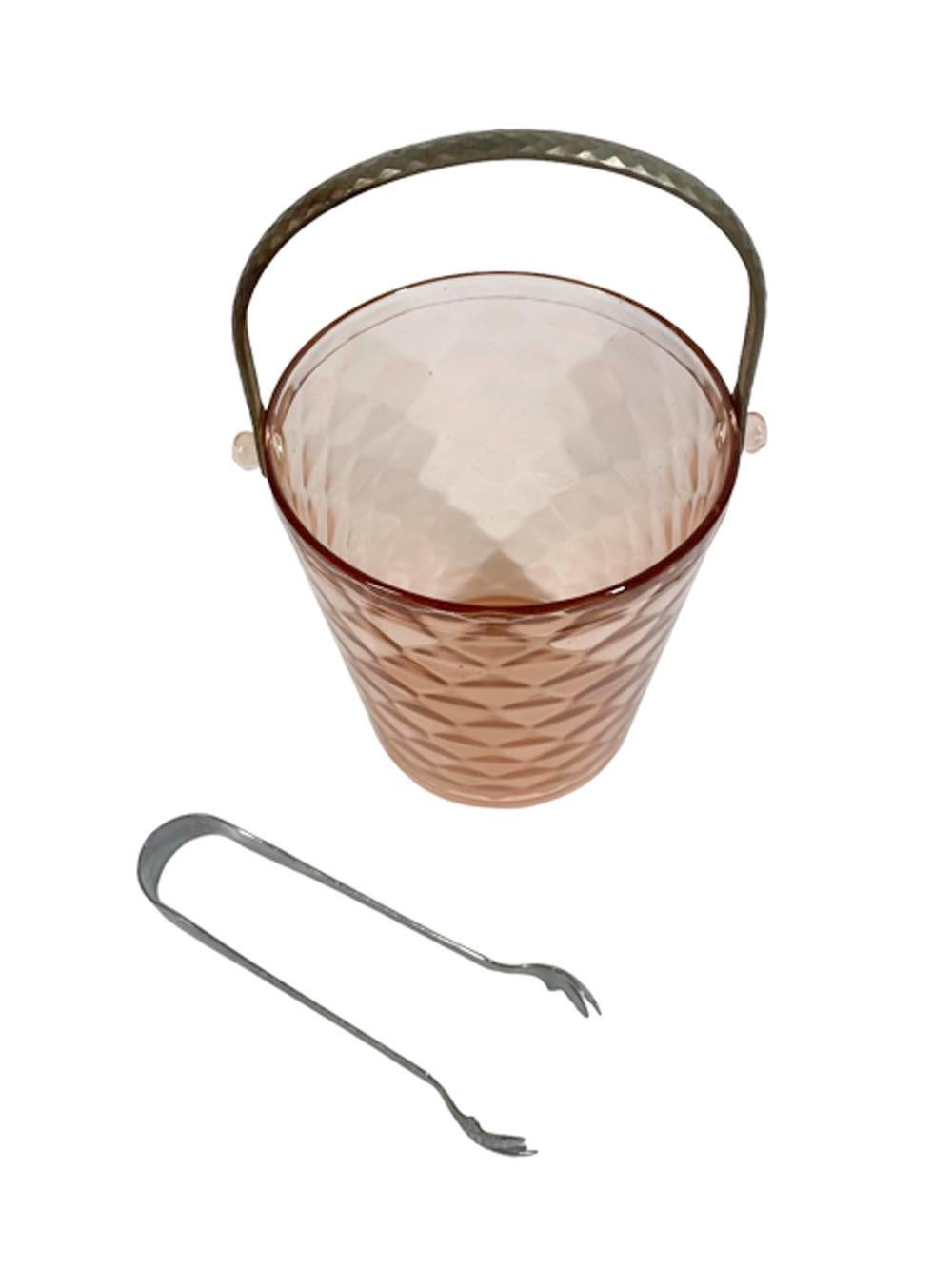 Art Deco pink glass Ice bucket in mold-blown optic diamond pattern, the rim with molded lugs to which the metal swing handle attaches. Ice tongs included.