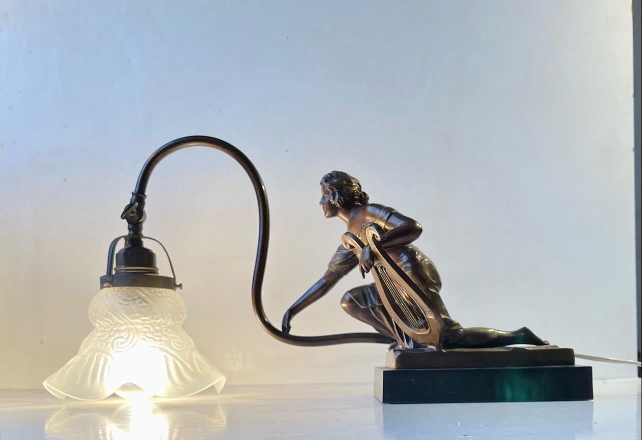 A beautifully crafted and detailed female harp player is the star of this pivoting and adjustable piano, shelf or mantle lamp. Its cast in bronze and rests on a indistinguishable signed black painted cast iron base. It features its original