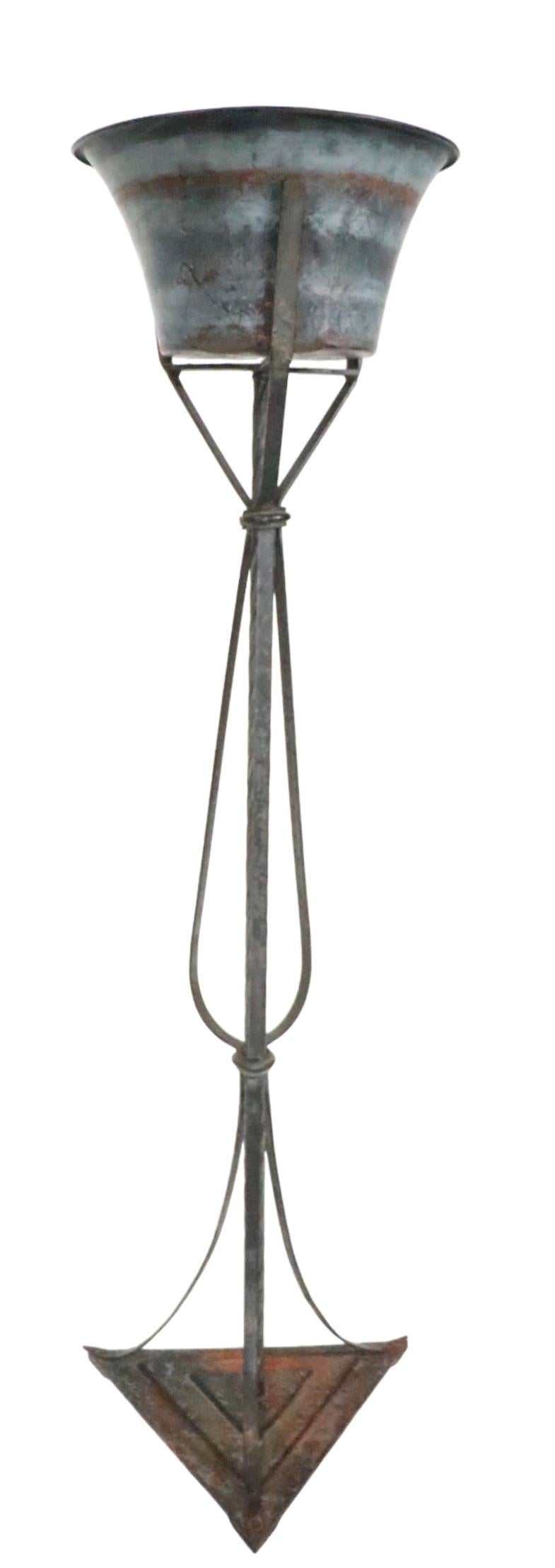 Jardinière classique Art Déco, avec son cache-pot en cuivre d'origine
 ( 11.5 Dia. x 6 H. pouces.  ) qui repose à l'intérieur du support. Le support vertical est construit en fonte, en fer forgé et en éléments en bronze. La finition est altérée et