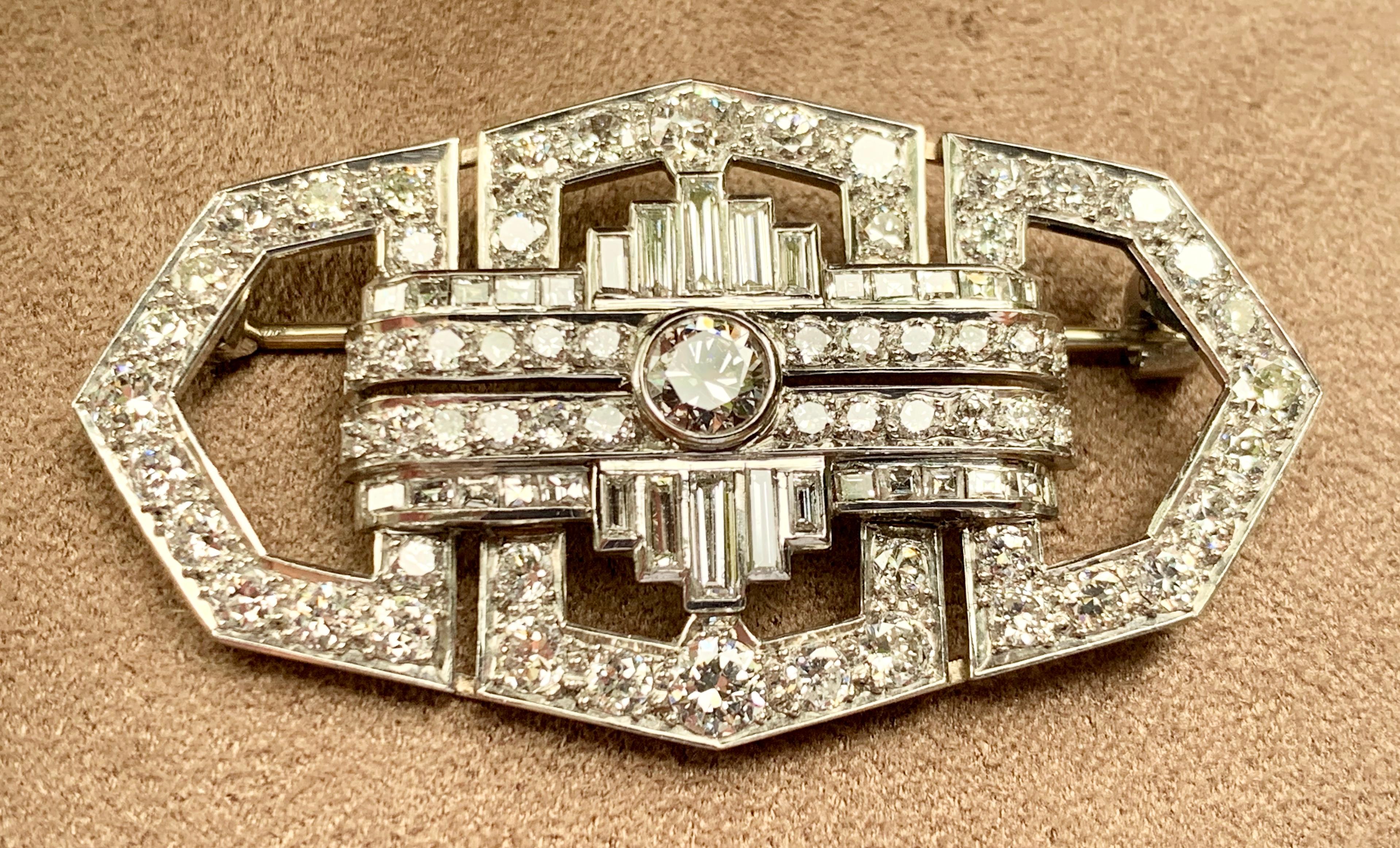 A classic 1920's  Art Deco diamond brooch in platinum; designed as a geometrically structured plaque around a central old mine European-cut diamond.   Approximately 4.6 cm long and set with approximately 5 carats of baguette and brilliant-cut