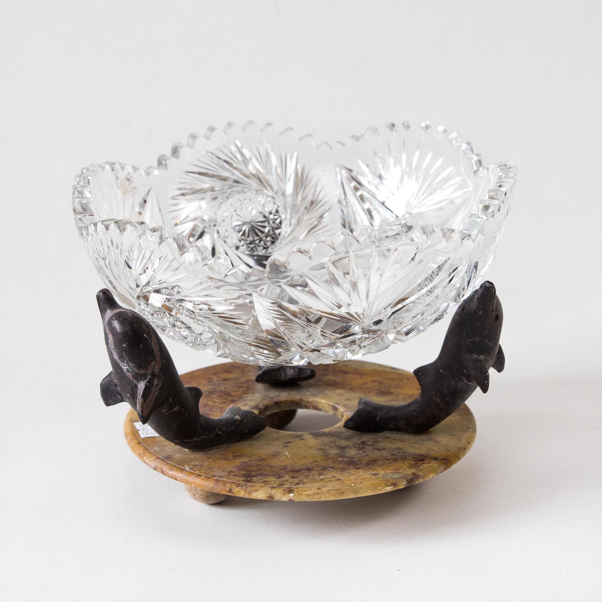 The unique plateau is the quintessence of the Art Deco style. It is characterized by a unique combination of dancing dolphins that support the crystal bowl as structural elements.

The basis is a round, stone plate in shades of melange, brown-gold
