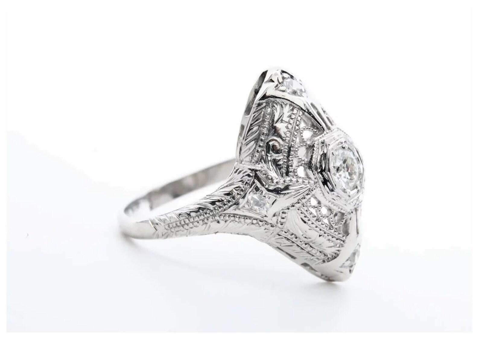 A handmade Art Deco period diamond filigree ring in platinum. Centering this dome style ring is a 0.20 carat old European cut diamond accented by four additional pave set diamonds. Grading as H color, VS clarity the five diamonds have a combined
