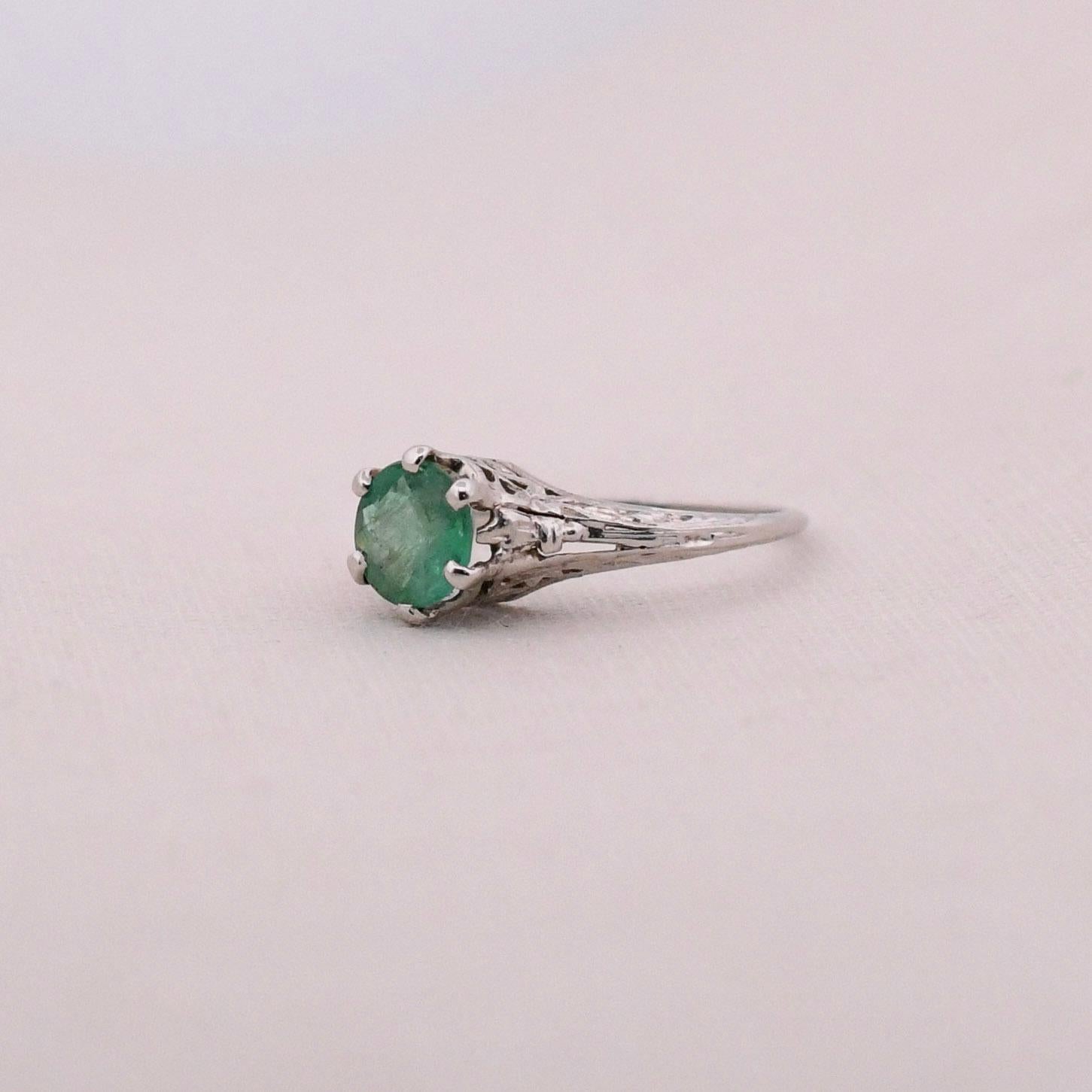 This unique gem is a stunning hue of green. Crafted in platinum this floral designed filigree ring has beautiful open work giving the overall piece a weightless feel. In the center of the six prong setting is perfectly paired with a round cut