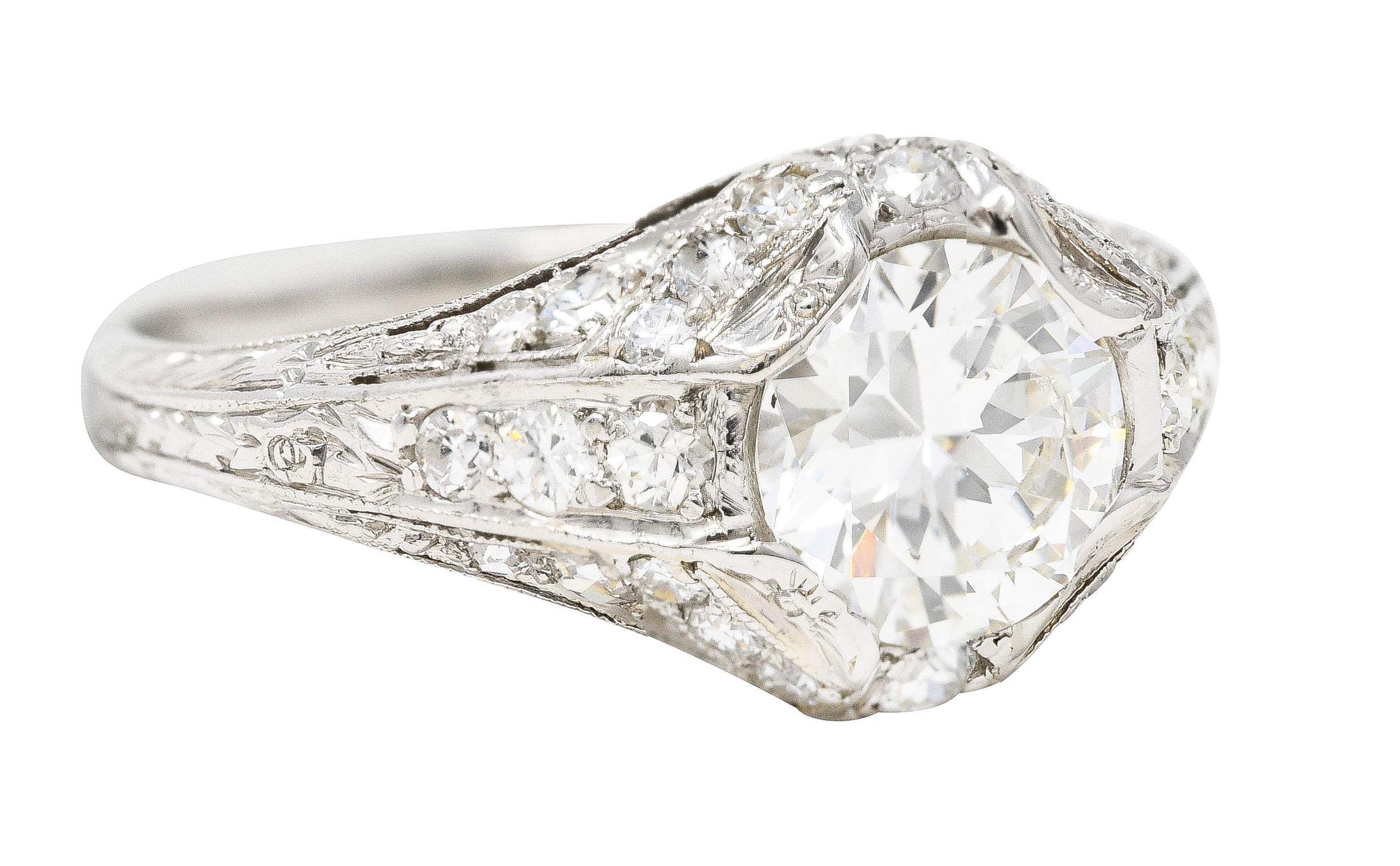 In der Mitte ein alter europäischer Diamant mit einem Gesamtgewicht von ca. 1,03 Karat - Farbe H und Reinheit SI1. Mit Zacken in einem durchbrochenen Milgrain-Detail eingefasst. Akzentuiert durch zusätzliche perlenbesetzte Diamanten im alten
