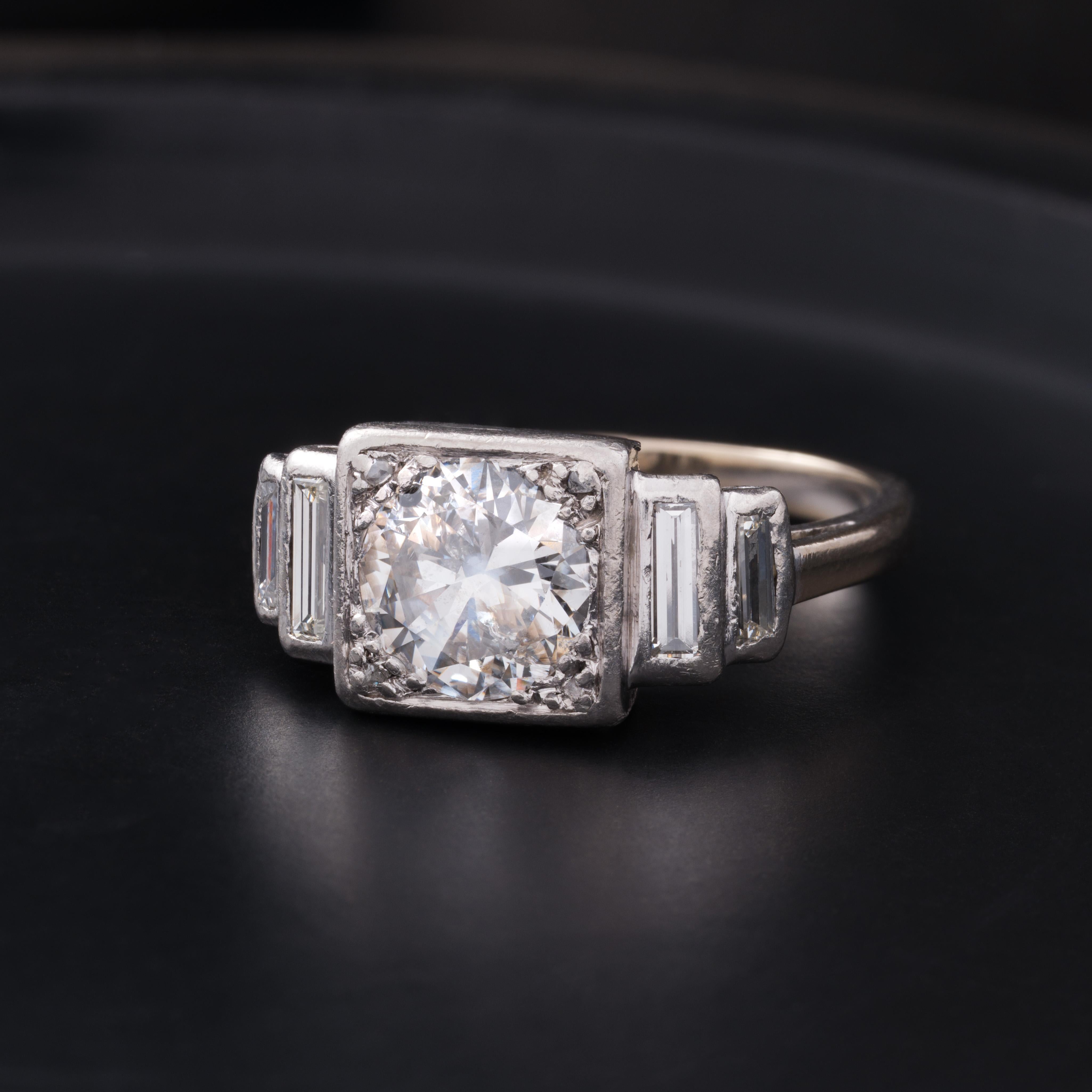 Bague de fiançailles en platine de style Art Déco tardif avec un diamant central de 1,55ct H, couleur I, pureté SI1, taille européenne ancienne et épaulements en diamant baguette. 
C.I.C. / taille 7