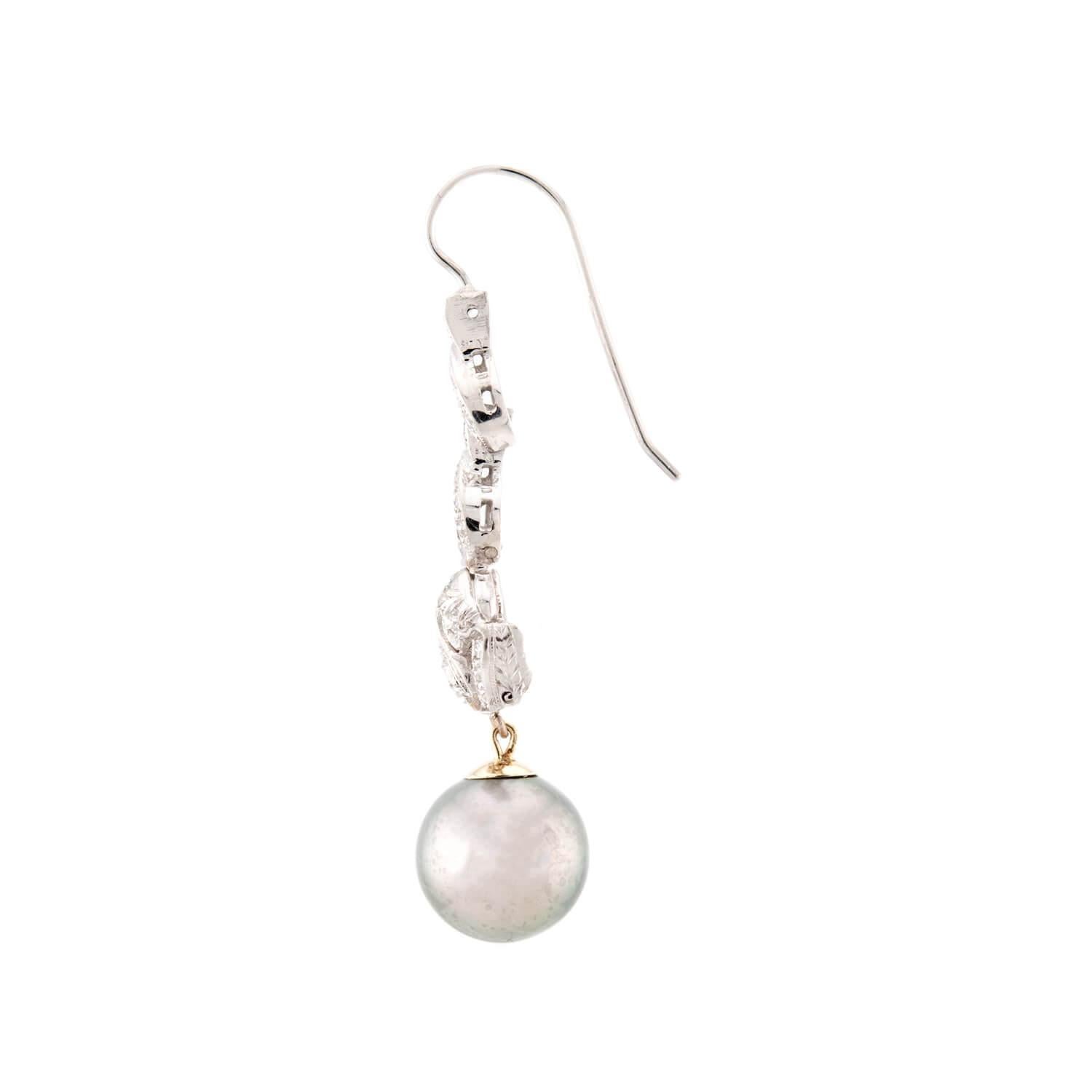 Un classico paio di orecchini con diamanti e perle dell'epoca Art Deco (ca. 1920)! Realizzato in platino e oro bianco 18 carati, ogni orecchino inizia con un componente lungo e sottile incrostato di diamanti taglio mina e taglio singolo incastonati.