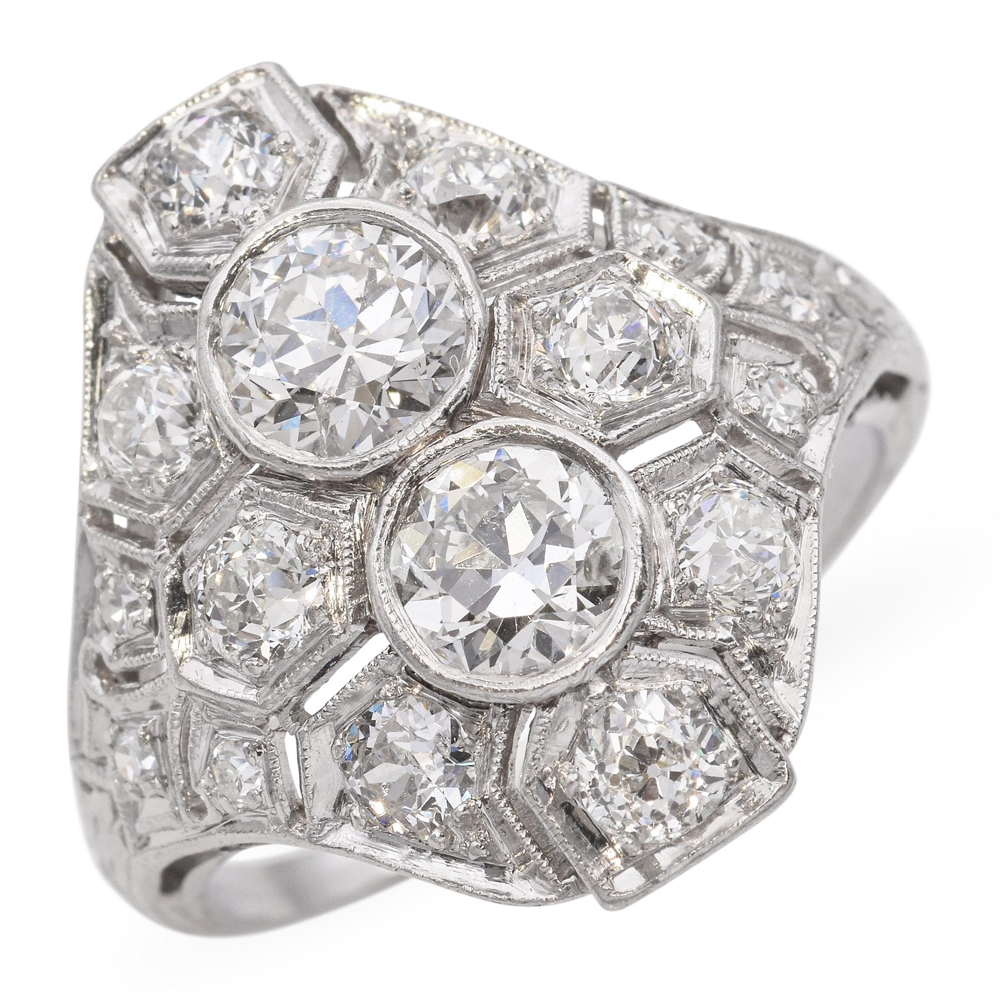 Cette étonnante bague Art déco en platine et diamants présente un motif géométrique frappant centré sur deux diamants de taille européenne ancienne, accentués par une constellation de pierres plus petites taillées dans des mines anciennes.