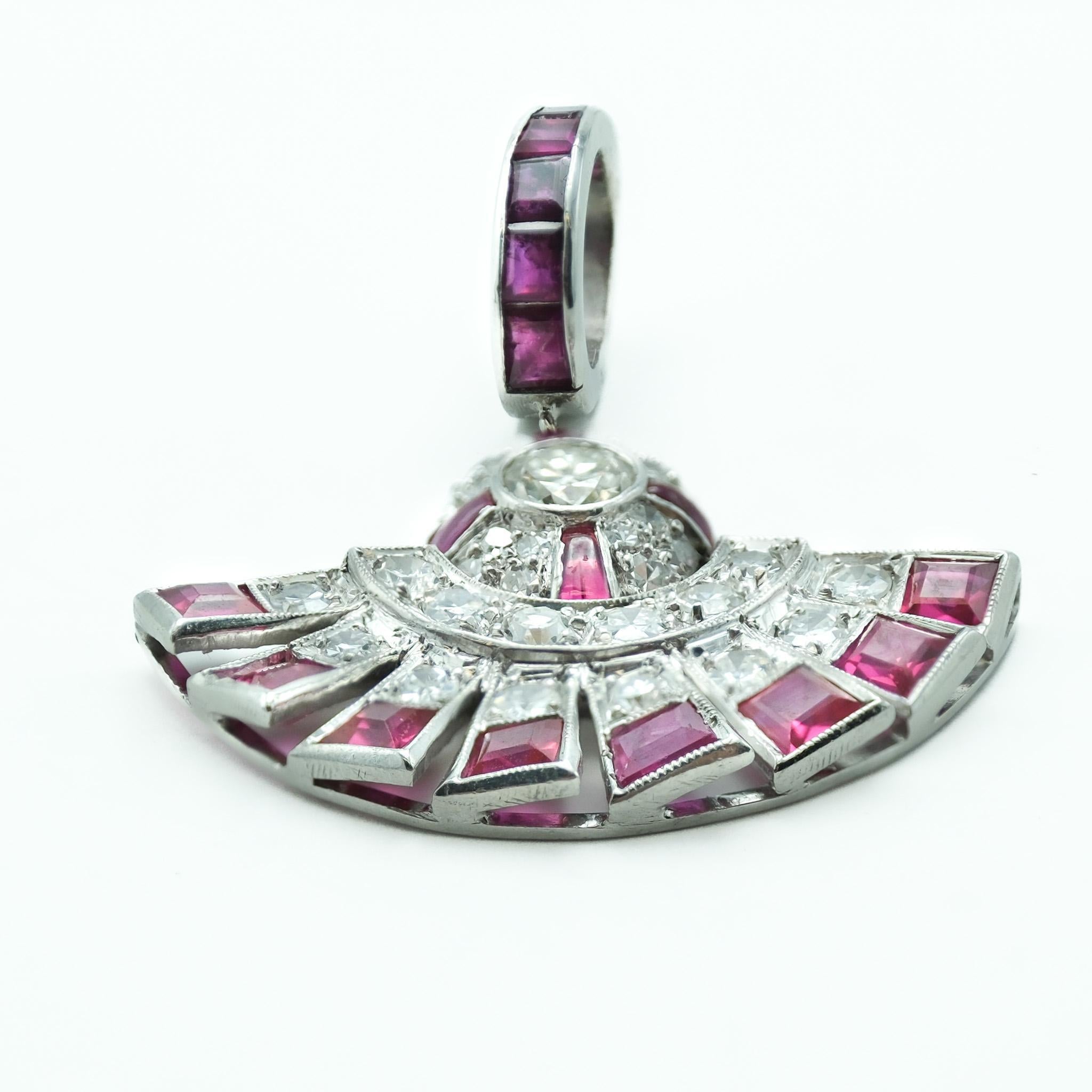 This pendant is a striking example of Art Deco design, showcasing the era's love for bold geometric shapes and lavish decoration. Crafted from platinum, a metal prized for its strength and luster, the piece features a fan-shaped motif that is both