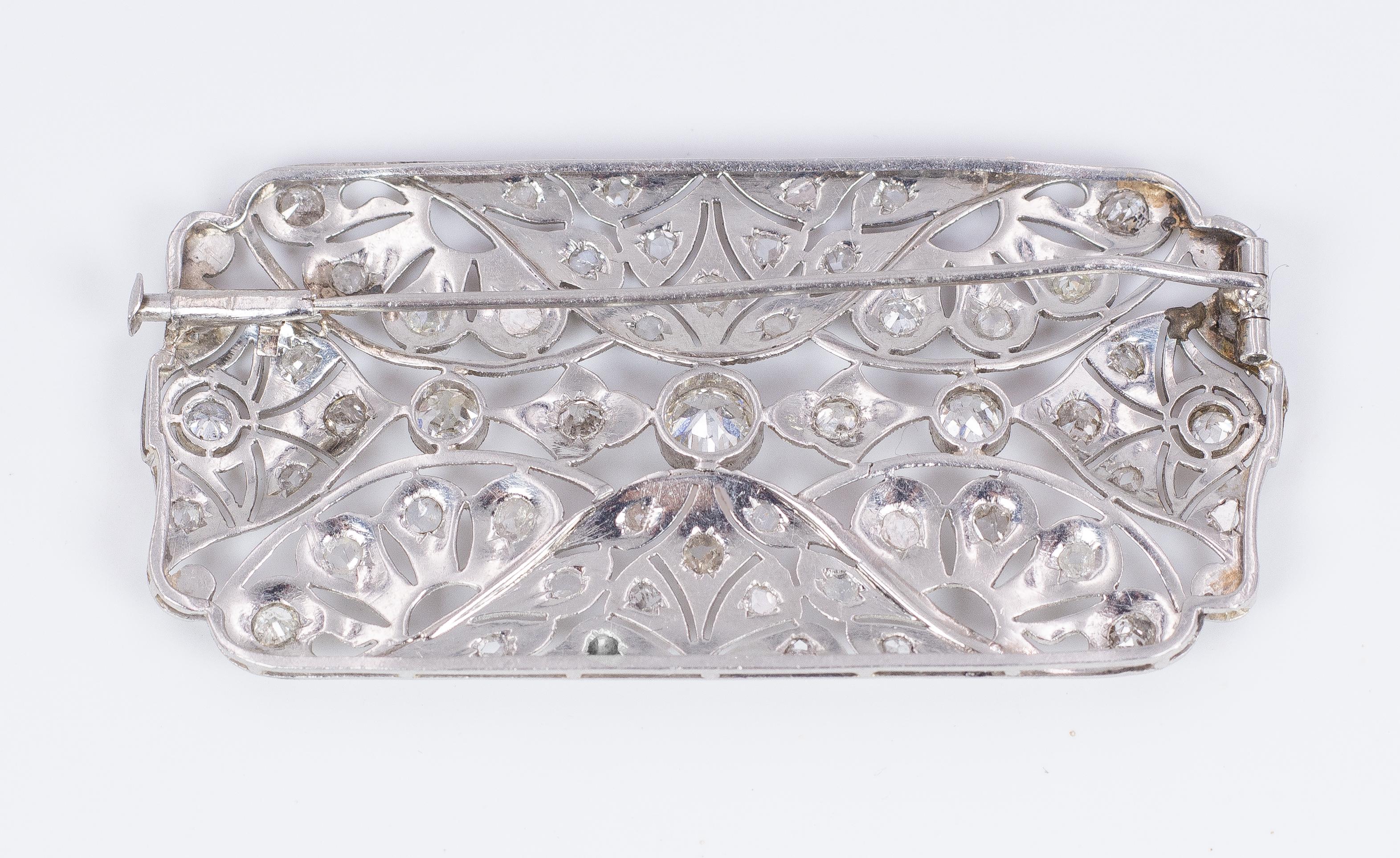 This stunning and very elegant antique brooch was created in the Art Deco period (1930s ca.): it is modelled in platinum and set with rose, old and round cut diamonds throughout (the central one is a round cut one). The brooch has a peculiar