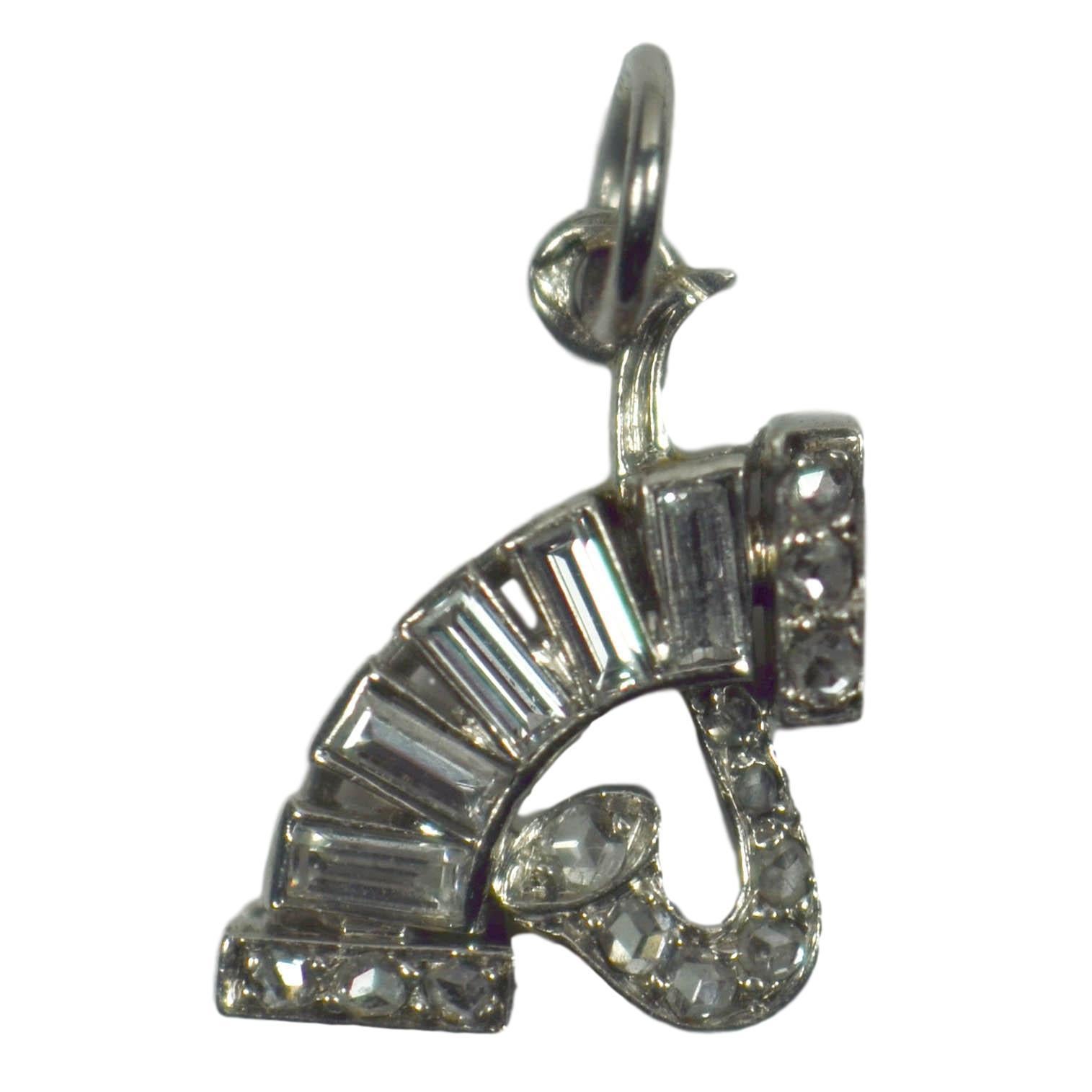An Art Deco platinum and diamond charm designed as a saxophone and accordion, possibly by Chaumet. Set with five baguette-cut diamonds and 13 rose-cut diamonds with a total approximate weight of 0.55 carats.

Stamped with the dogs head for platinum