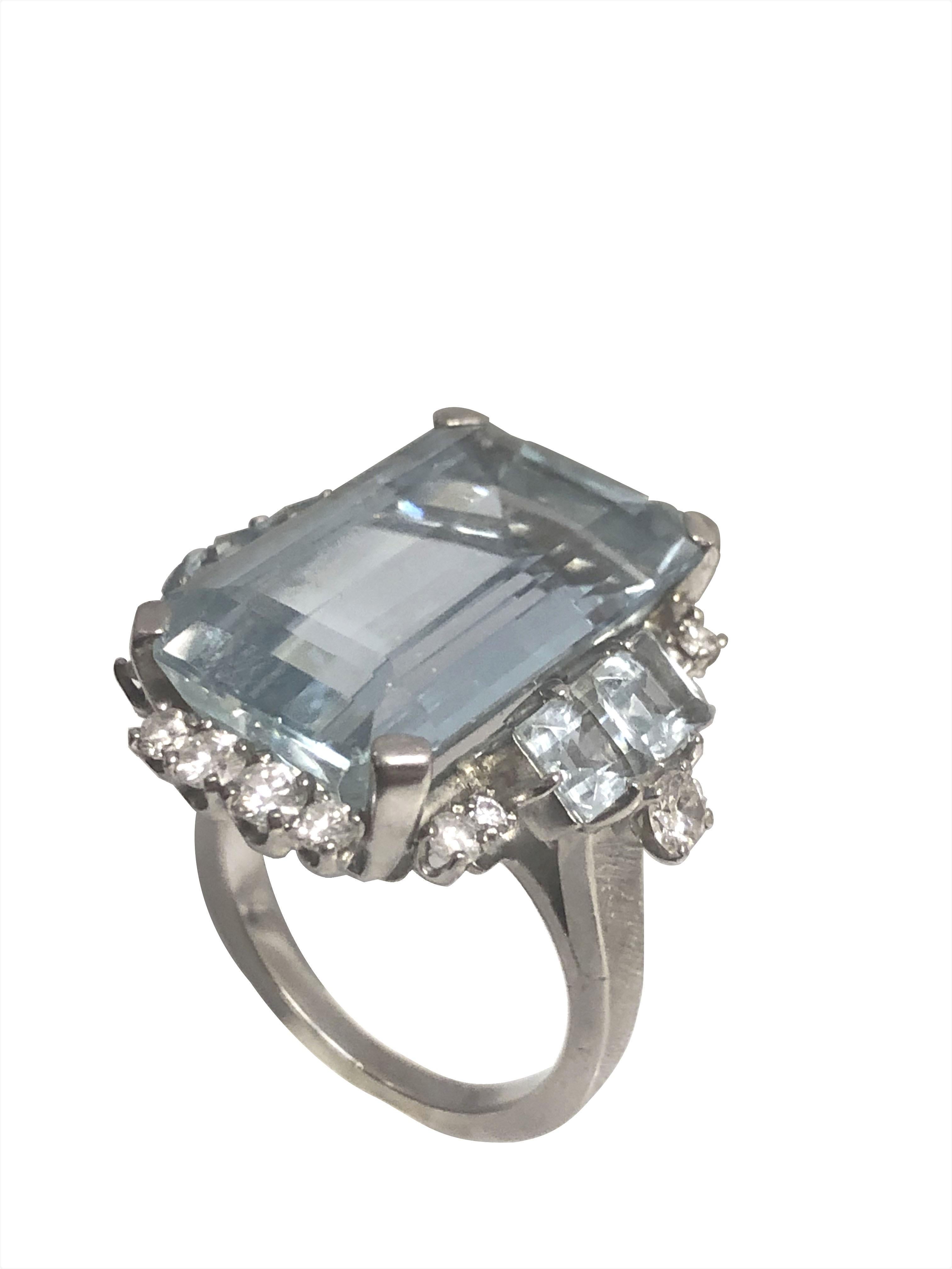 Circa 1940 Platinum Art Deco Ring, centrally set with a Step - Emerald cut Aquamarine of very fine color and measuring 20 x 12 MM approximately 14 Carats, the sides of the ring are set with 4 Square step cut Aquamarines and further set with numerous
