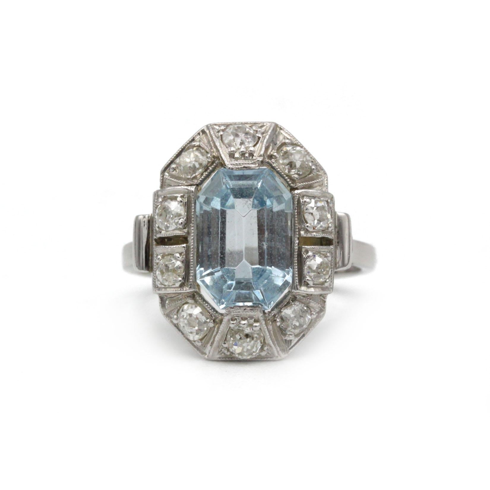 Adopta la elegancia de los locos años veinte con este anillo francés Art Decó de platino, centrado en una cautivadora aguamarina talla esmeralda de aproximadamente 4,00 cts. La gema azul gélida está enmarcada por diez diamantes tallados en mina