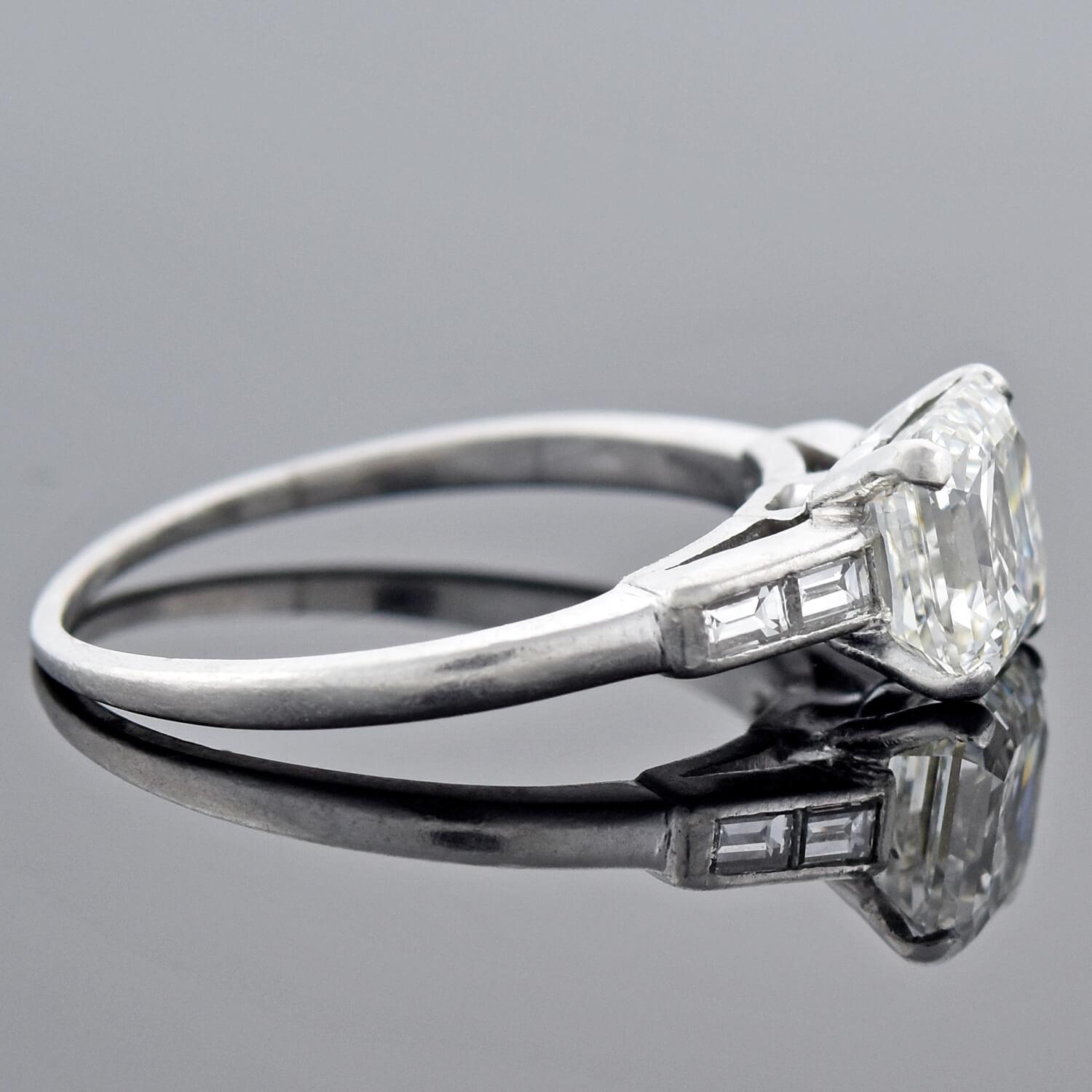 This diamond engagement ring from the late Art Deco (ca1930s) era is a breathtaking beauty! Resting at the center of a platinum setting is a stunning 1.50ct Asscher Cut diamond. This particular modification of an Emerald Cut diamond is also known as