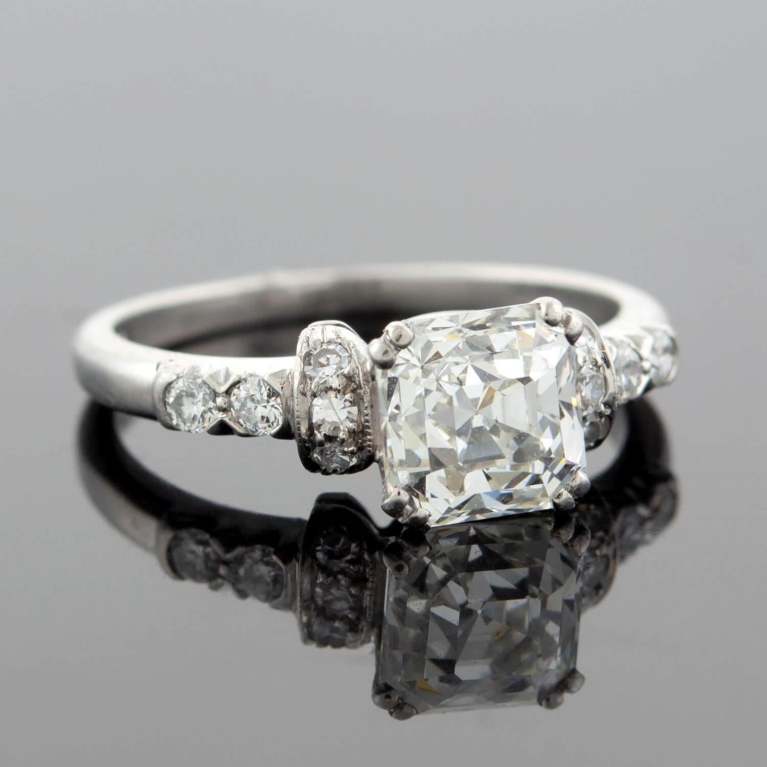 This diamond engagement ring from the late Art Deco (ca1920s) era is a breathtaking beauty! Resting at the center of a platinum setting is a stunning 1.52ct Asscher Cut diamond. This particular modification of an Emerald Cut diamond is also known as