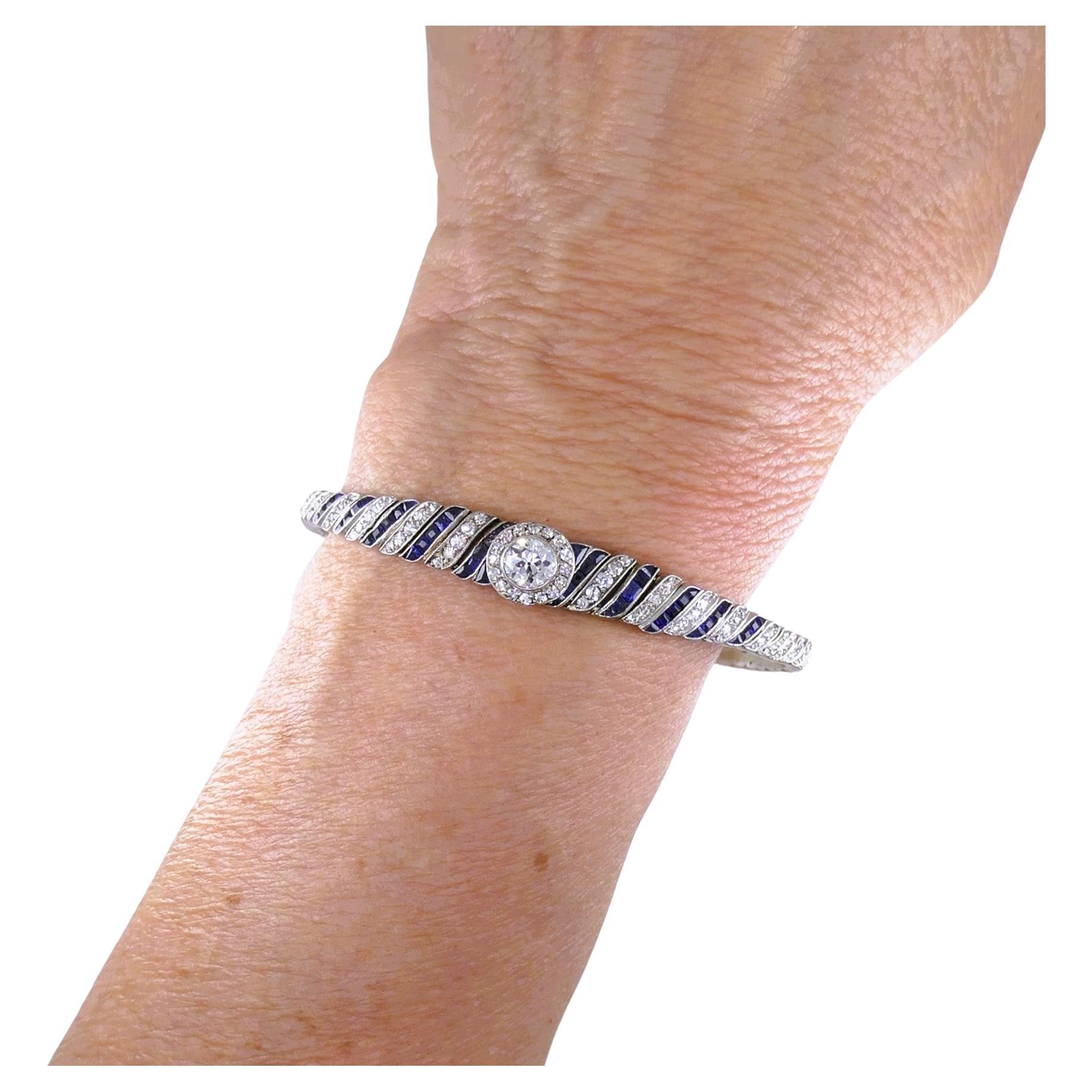 Magnifique bracelet Art déco en platine, orné d'un diamant de taille Old European, rehaussé de saphirs de taille table et de diamants de taille unique.
Le bracelet porte un motif tourbillonnant, composé de rubans de diamants et de saphirs alternés.