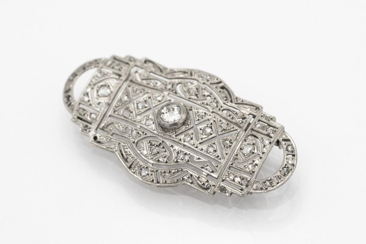 An old, elegant Art Deco brooch with diamonds in an old diamond and rosette cut.

A brooch made of platinum, white gold and silver elements, decorated with as many as 45 diamonds with a total weight of 0.57ct.

A central diamond in an 