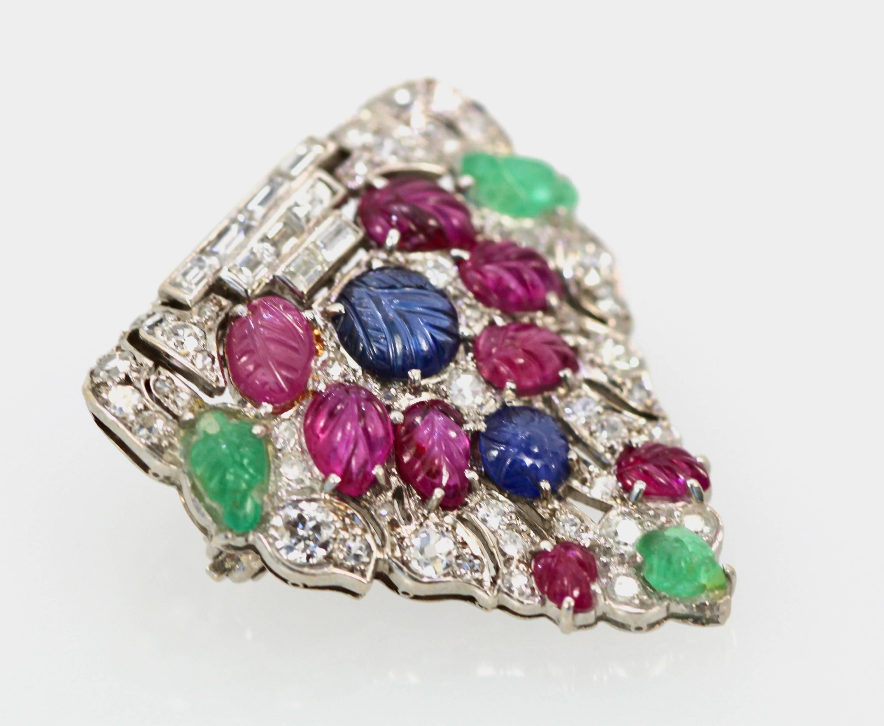 Art Deco Platinum Carved Ruby, Sapphire, Emerald and Diamond Pierced Shield Brooch

This Deco Platinum Brooch is in excellent condition. This is a pierced shield shaped Brooch is set with nine (9) baguette and 42 round and single cut Diamonds