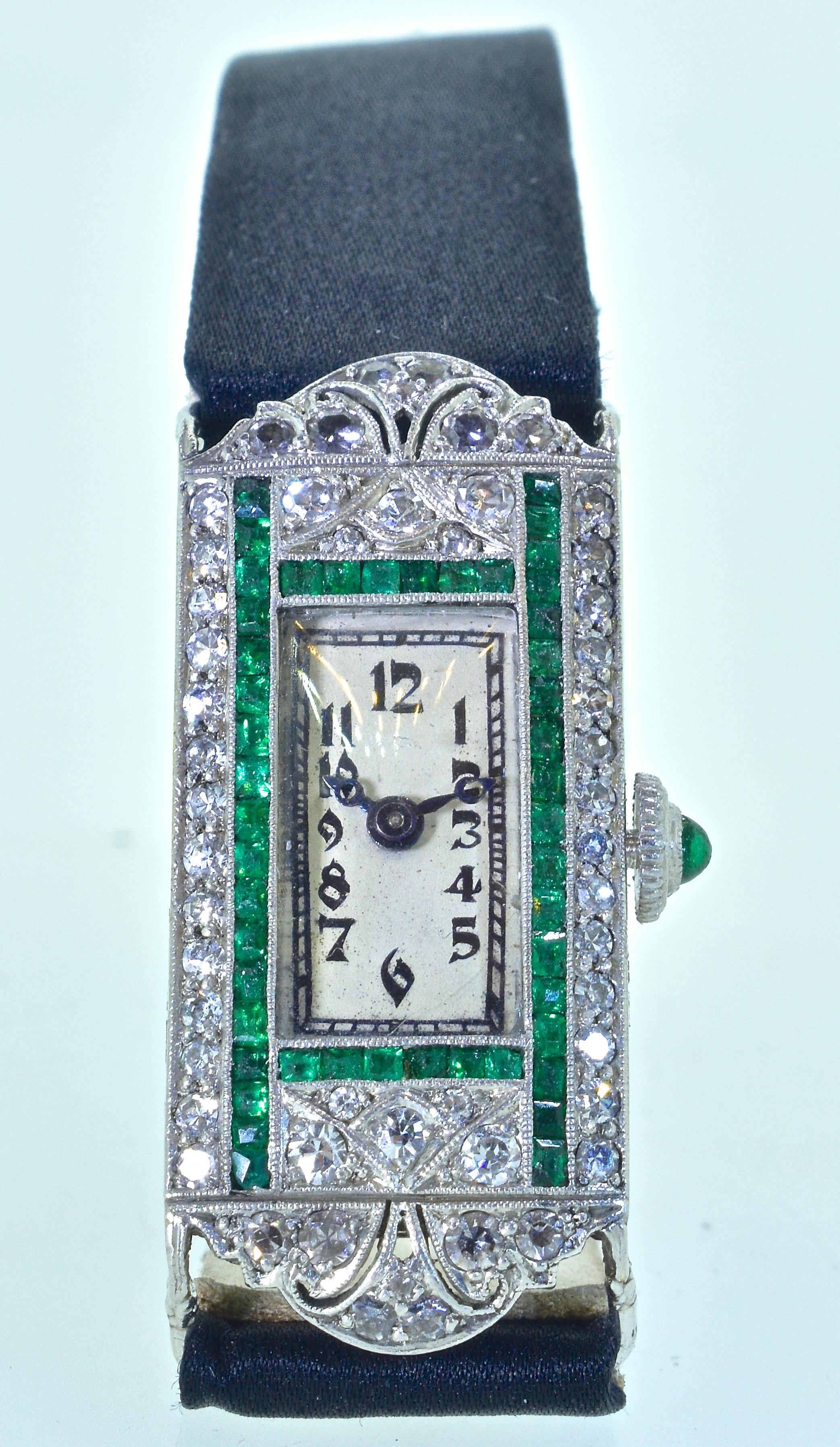 Art Deco wristwatch composed of diamonds and calibre cut emeralds.  In platinum with highly engraved sides, this wristwatch which is in fine condition, recently serviced, and guaranteed for a year.  The movement is by Cart. A fine Swiss watch maker.