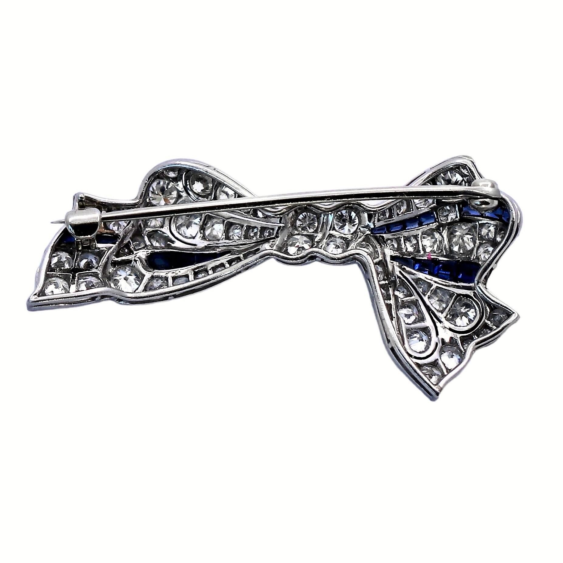 This lovely, platinum, Art-Deco period bow brooch is highly detailed and articulated, with impeccable mill graining.  It is set with very symmetrical, European Cut diamonds of overall G color and VS2 clarity. Total approximate diamond weight is